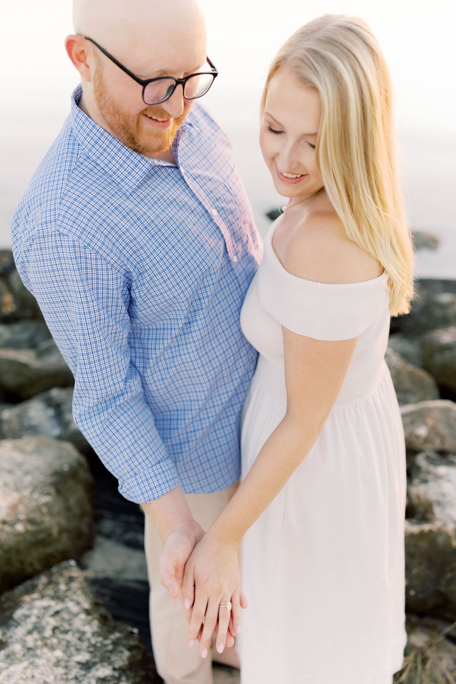 Intimate close-up shots of couple against coastal rocks and bright sky.