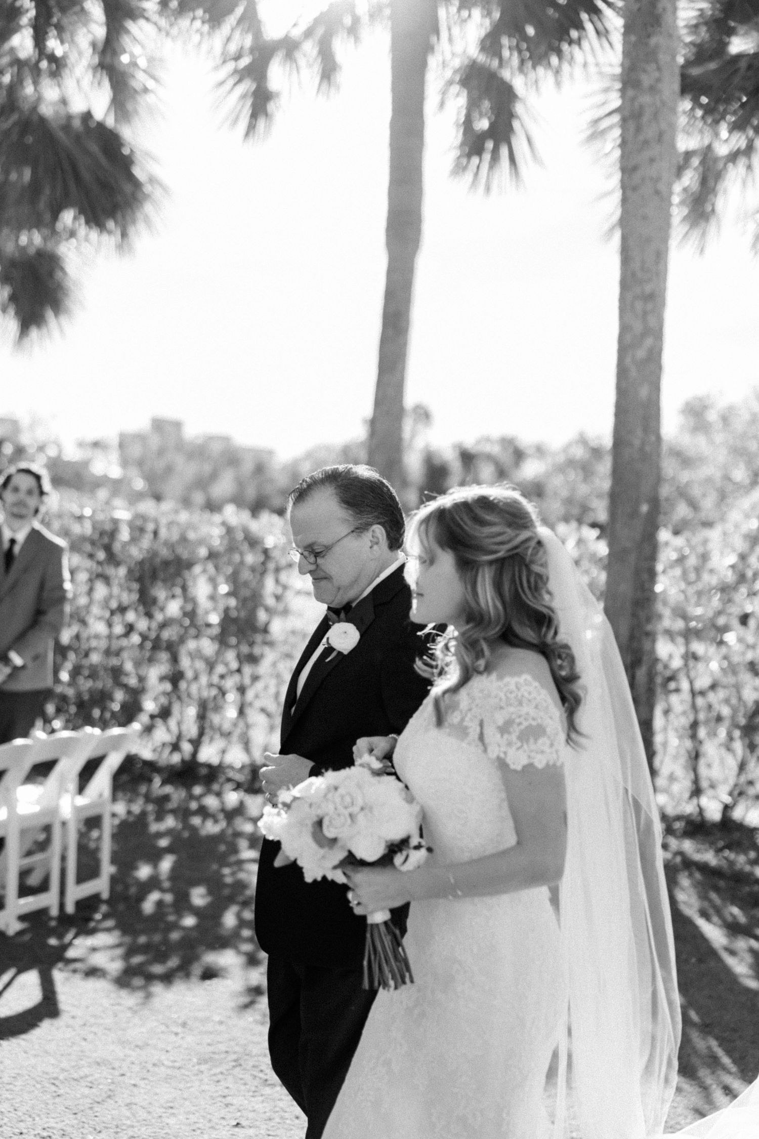 Black and white wedding portraits captured among palm trees during an outdoor ceremony.