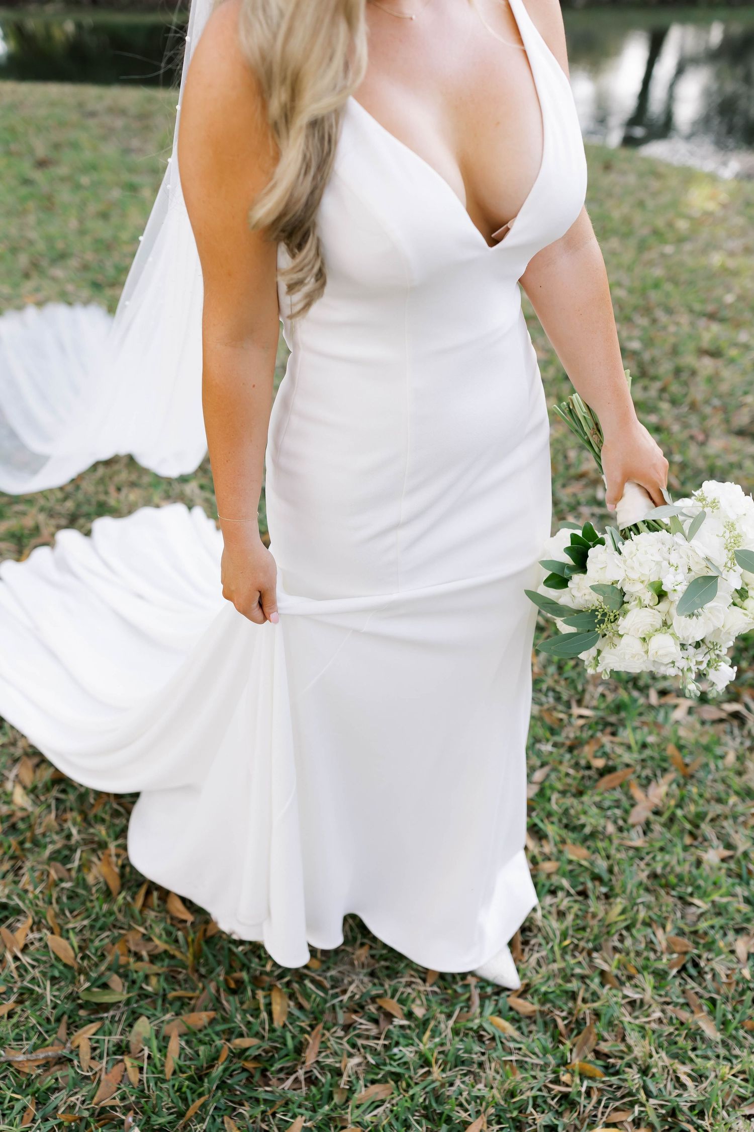 Detail shots of white wedding dress flowing over grass and leaves.