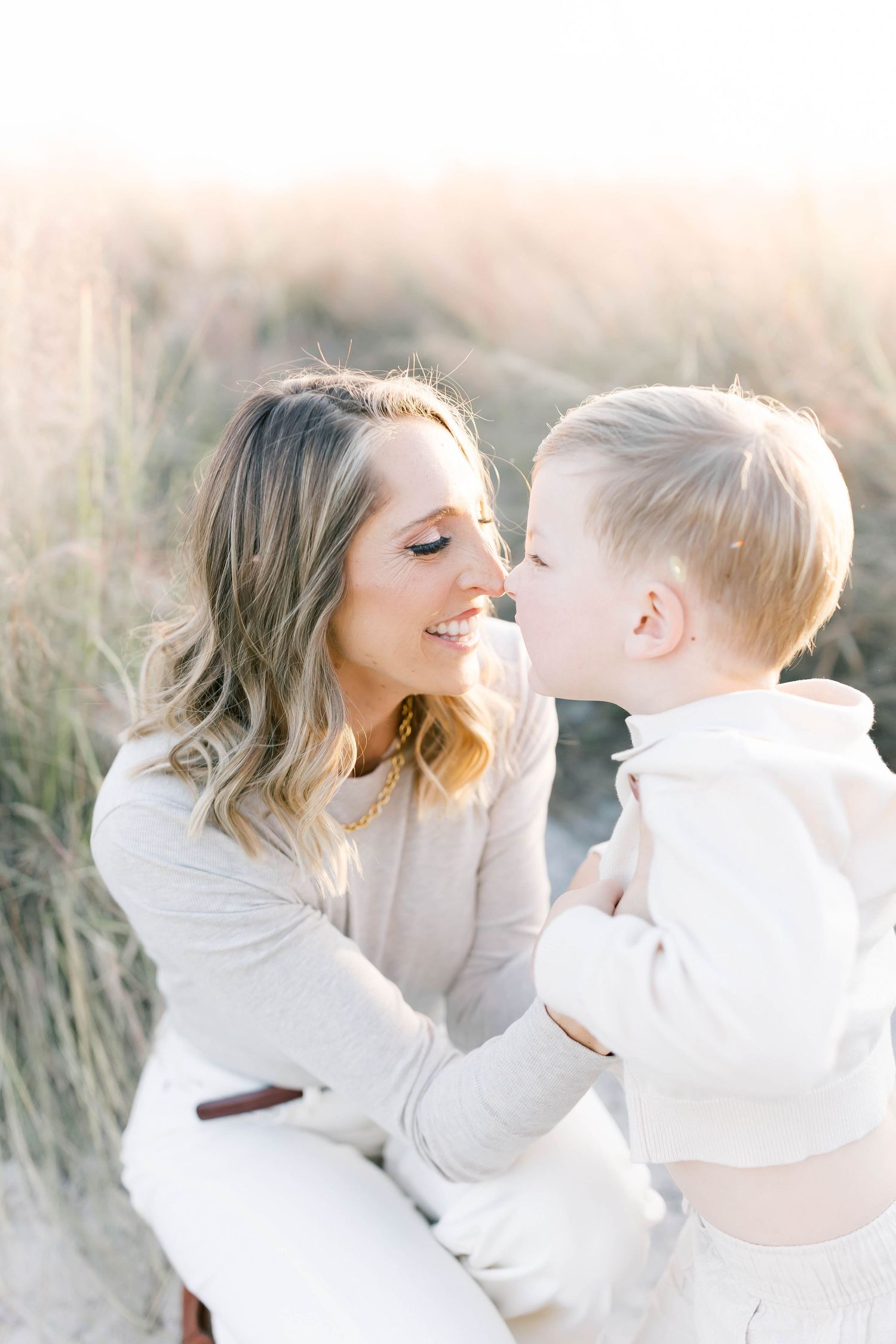 A tender moment between parent and child in soft white clothing during sunset.