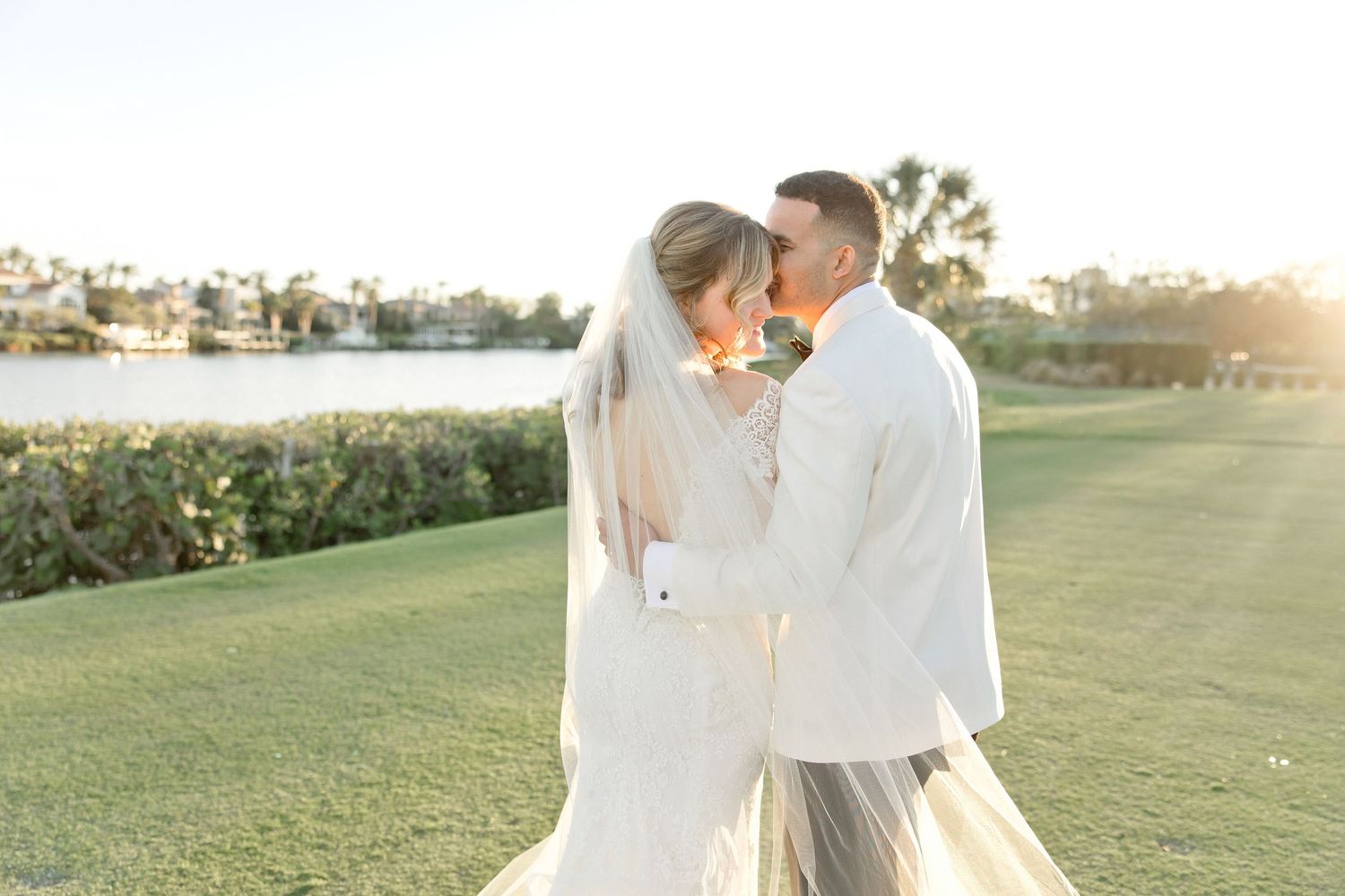 A sunset wedding photo captures a tender moment on a waterfront golf course.