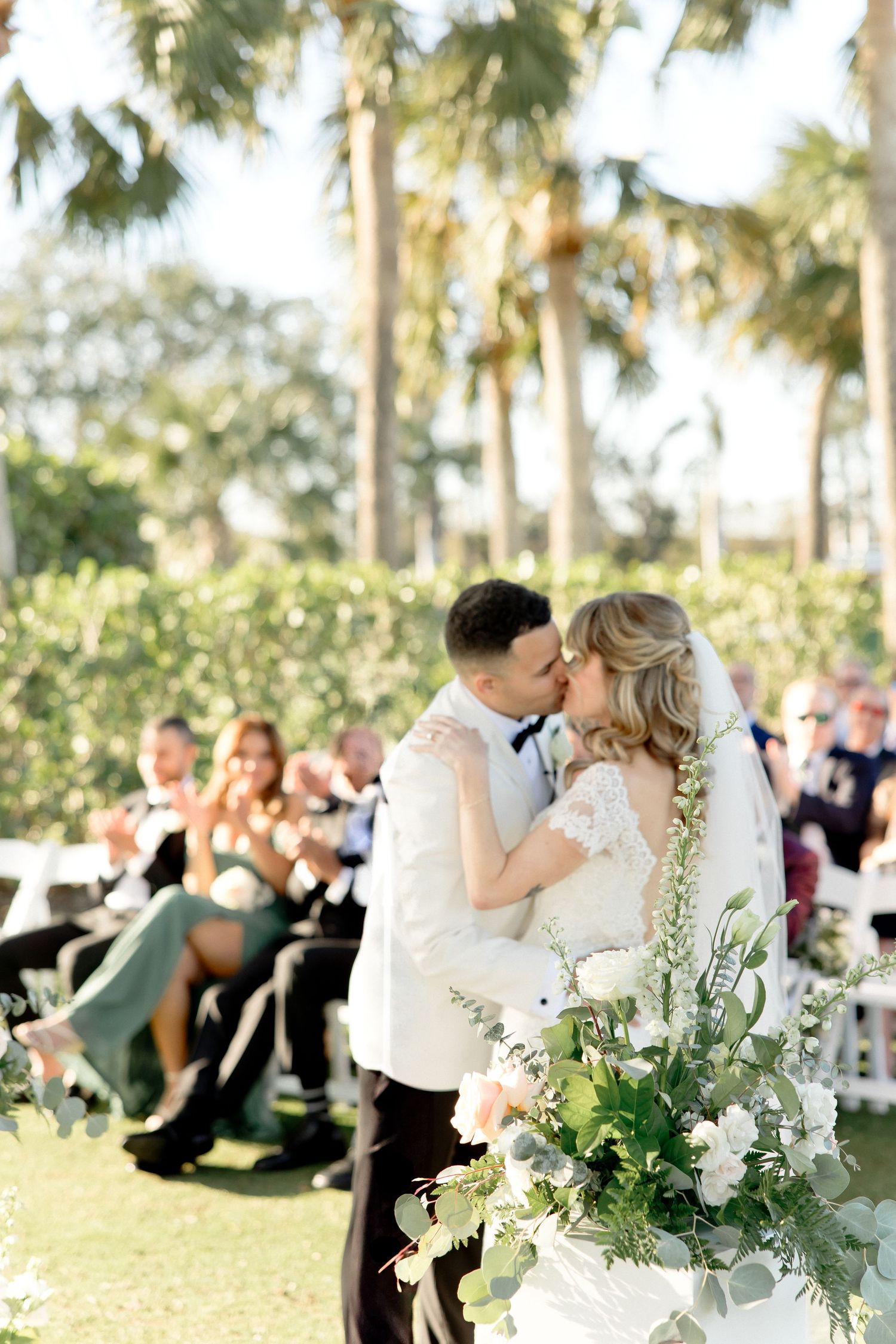 Outdoor wedding ceremony with palm trees and floral arrangements.