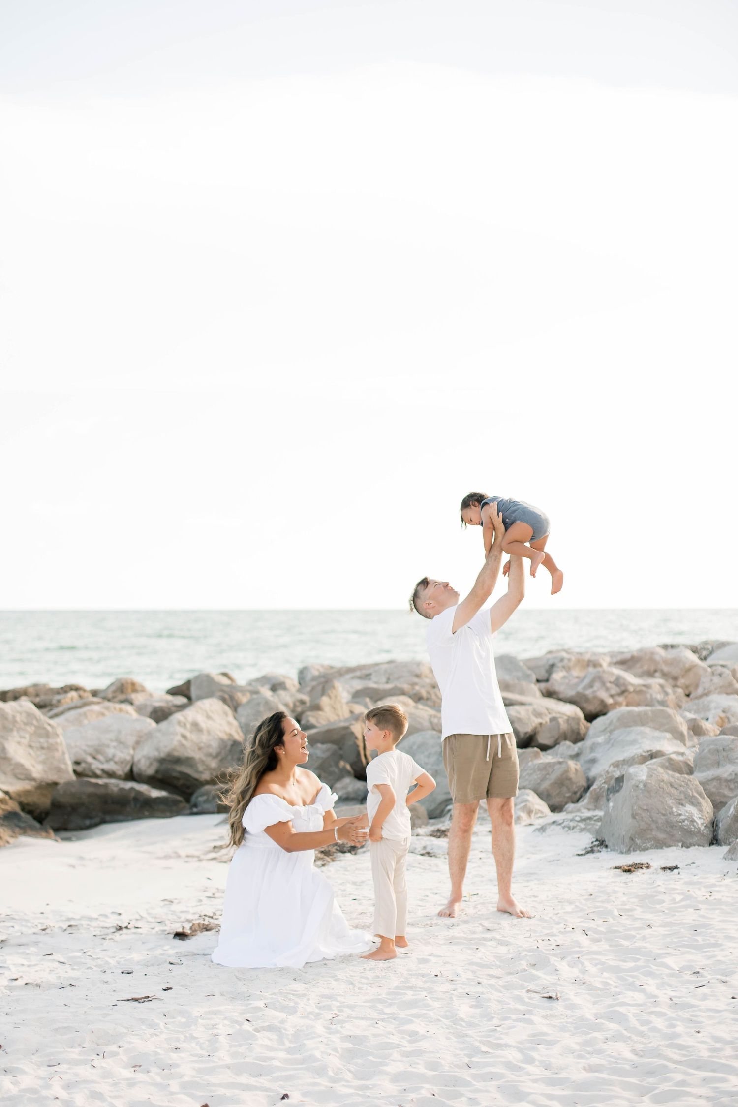 Family enjoying playtime together on a beach with large rocky formations.