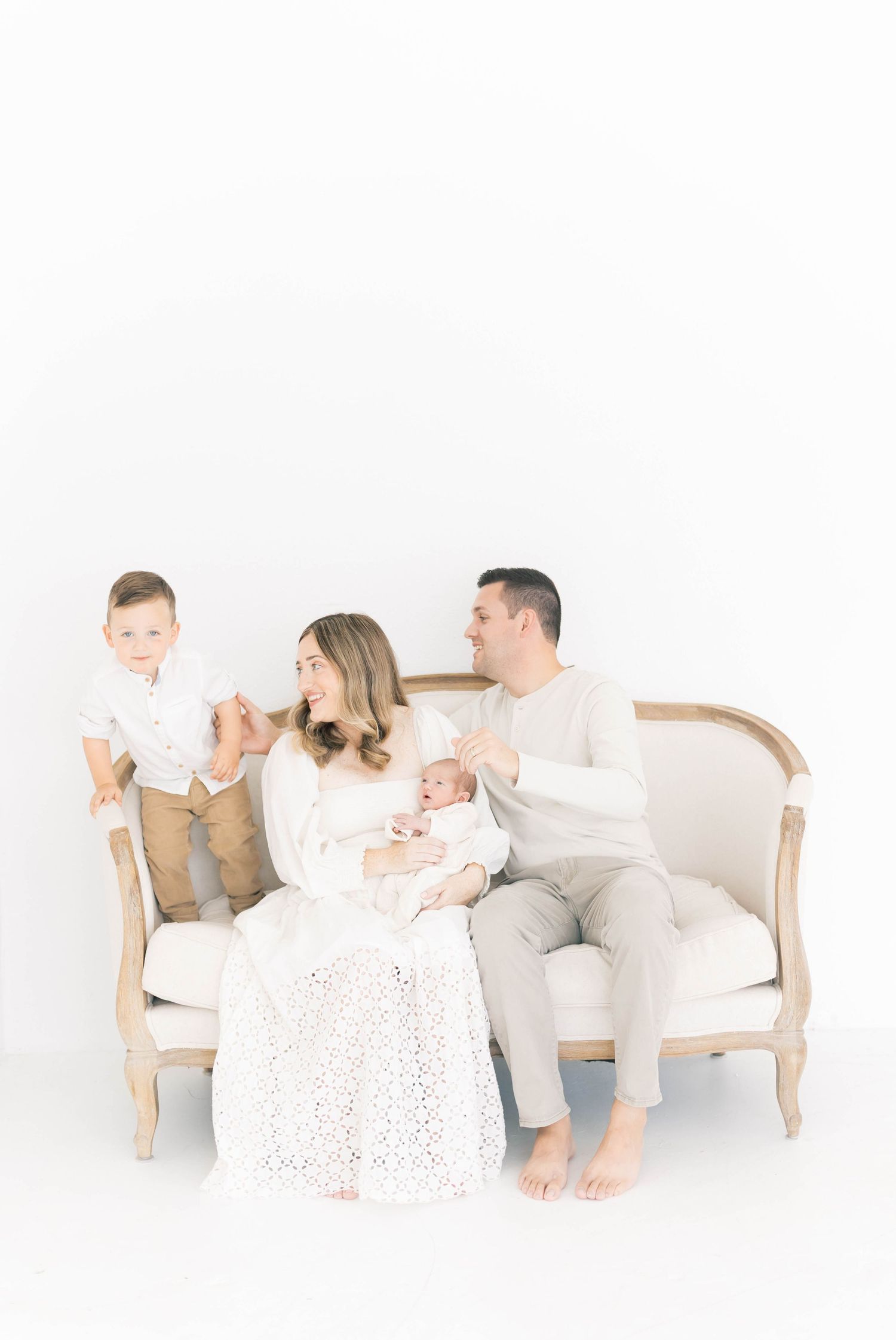 Family lounging together on vintage sofa during minimalist photo session.