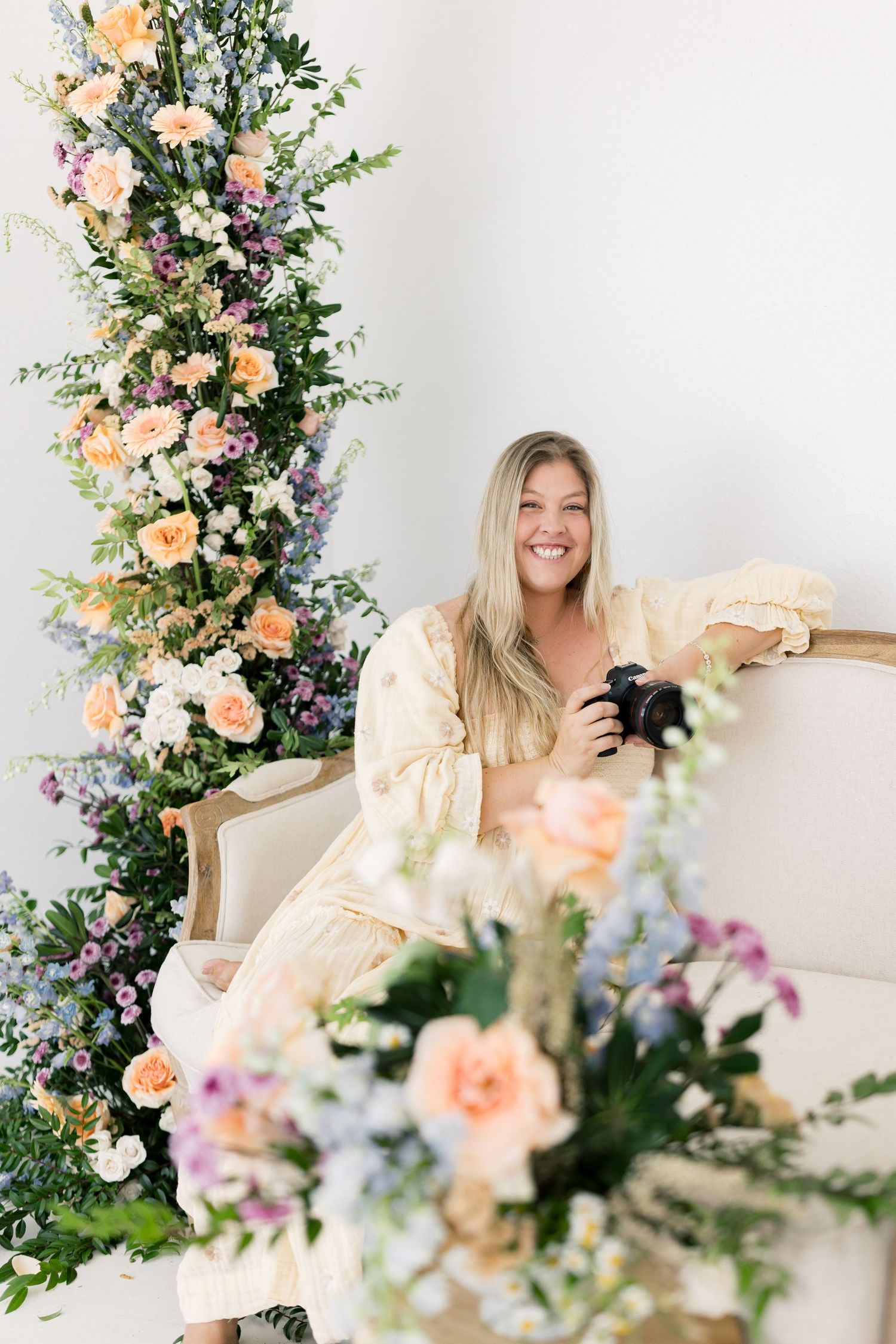 Floral arrangement with peach roses and mixed blooms against white backdrop.