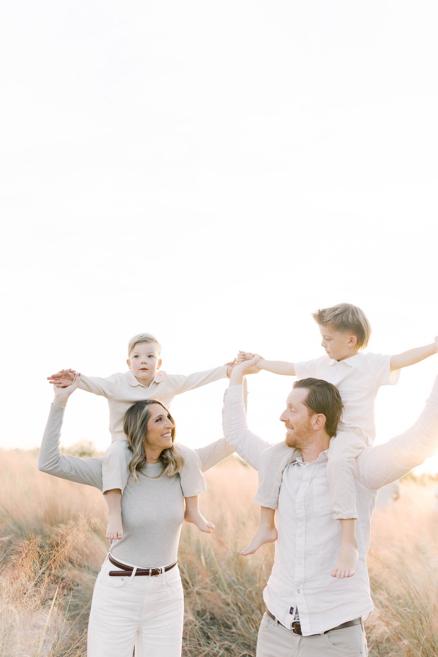 Family dressed in white and beige shares joyful moments in nature.