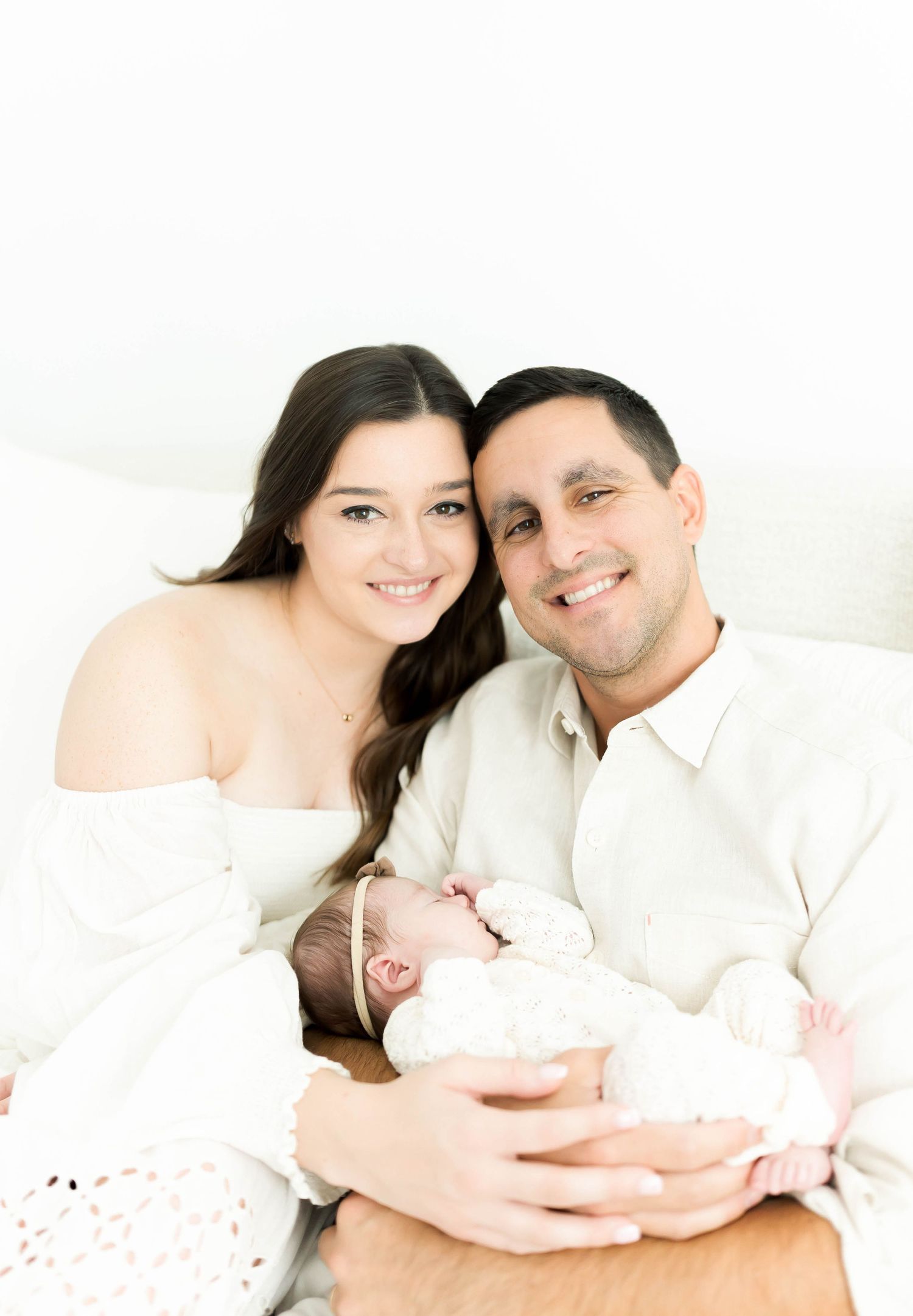 Family portrait series showing tender moments with newborn in white attire.