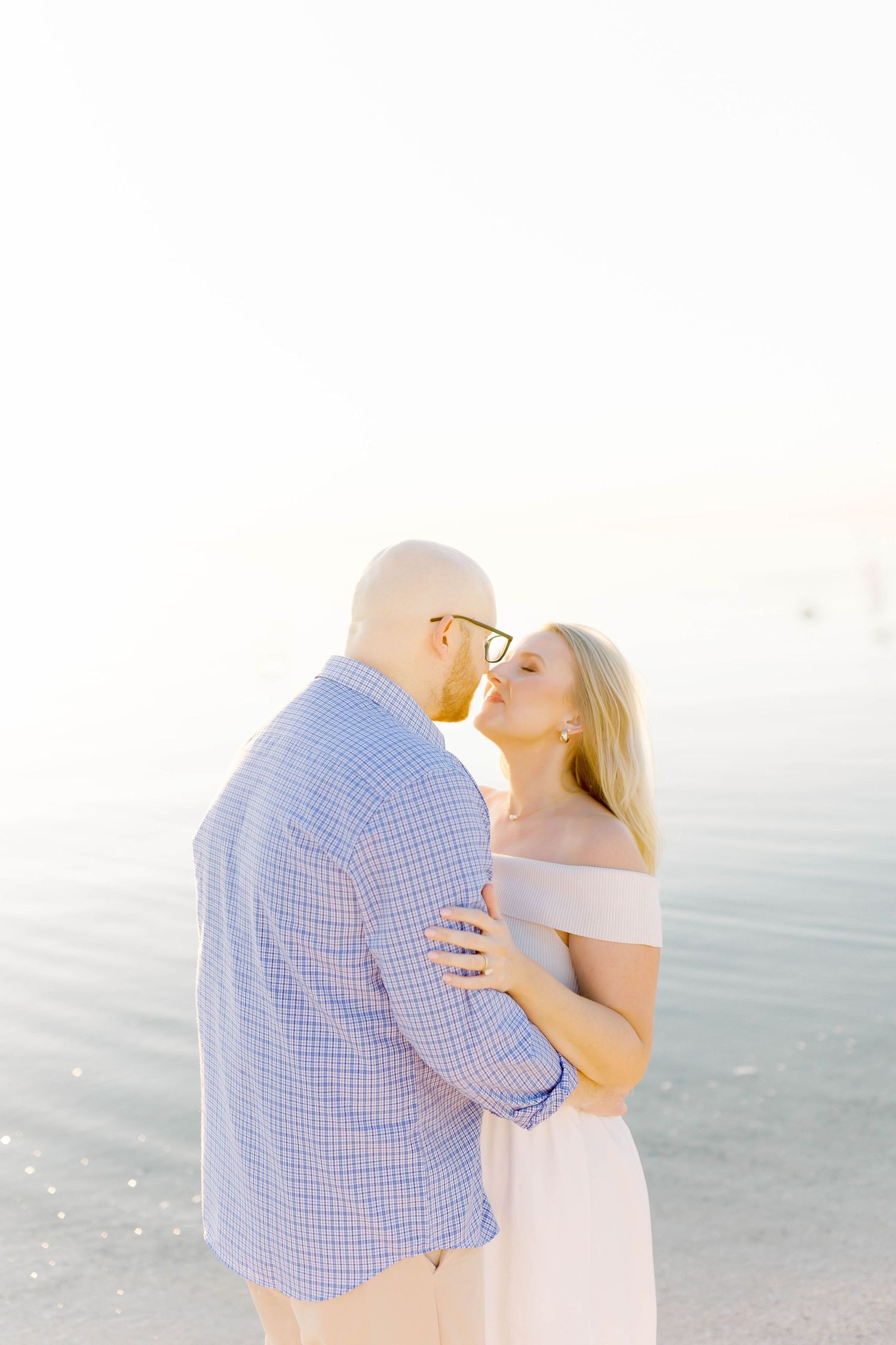 Couple sharing tender moment during sunset beach photoshoot.