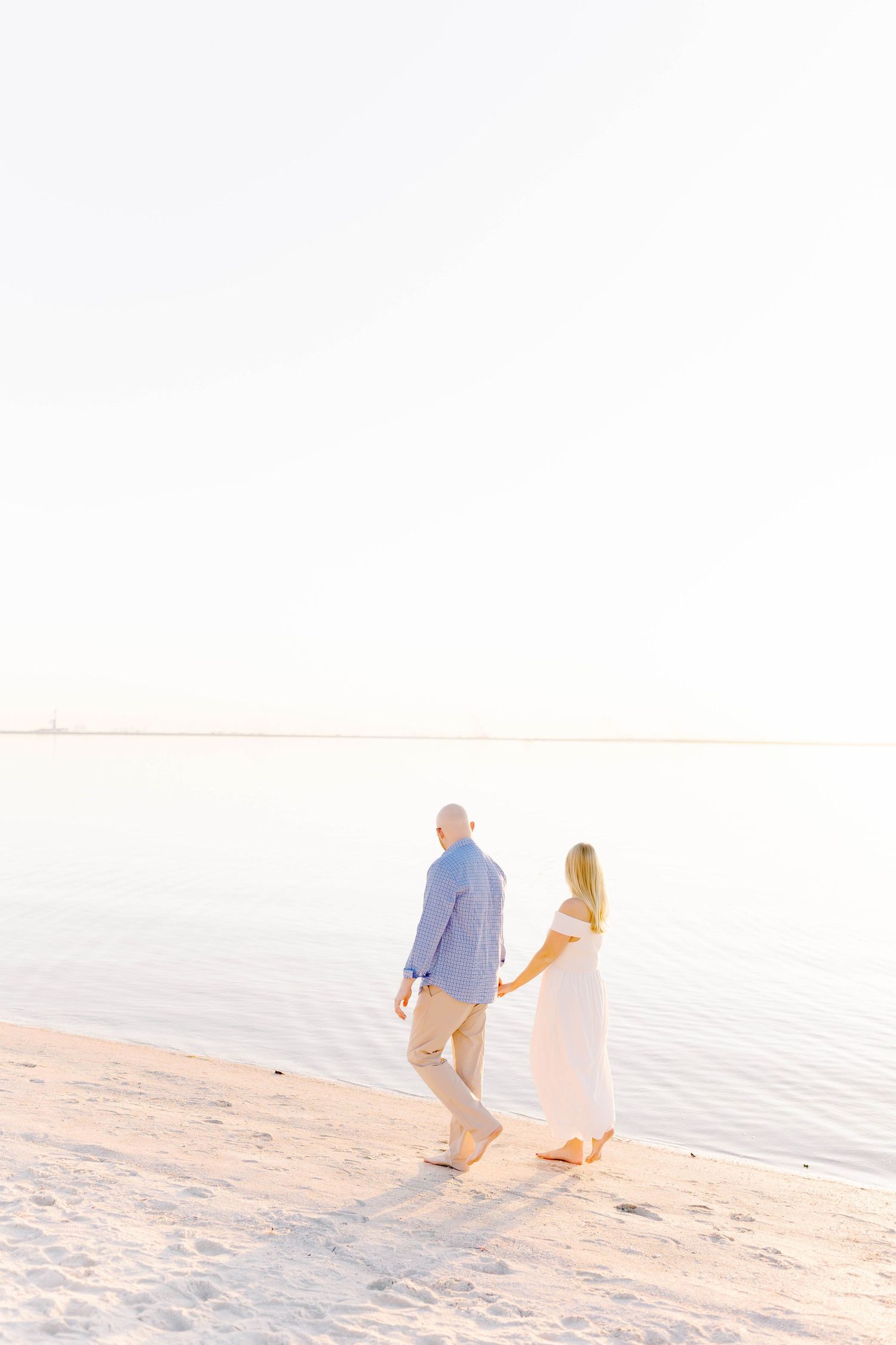 Silhouetted couple walking along the shoreline at sunset.