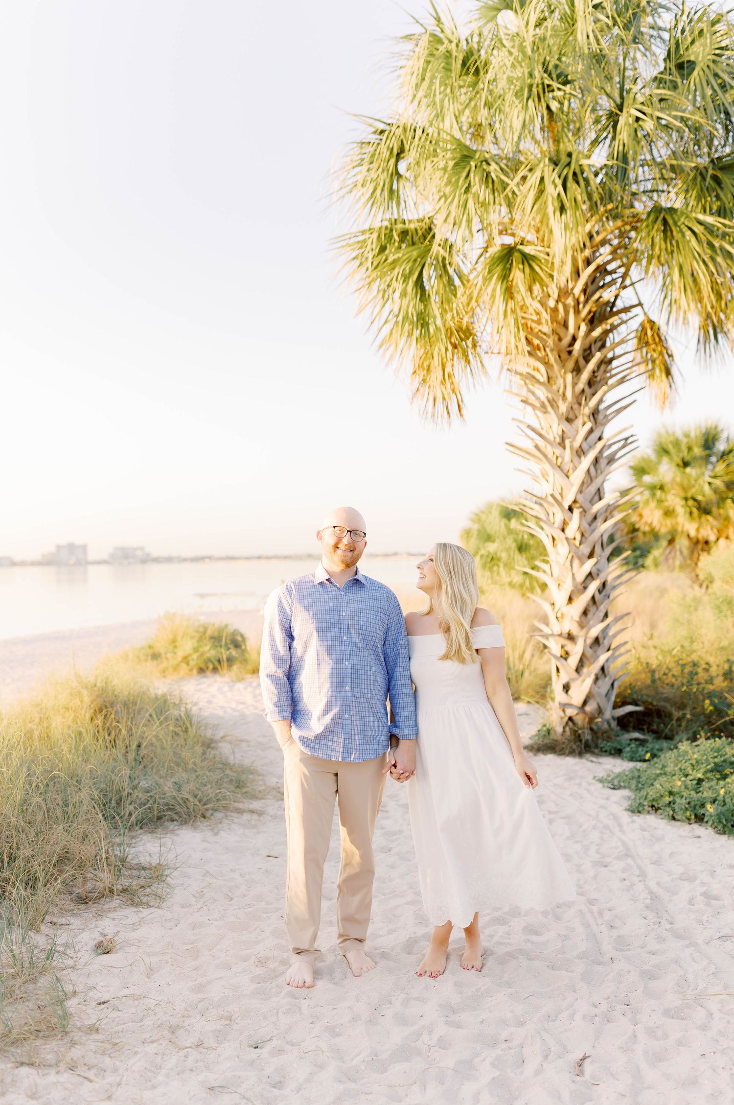 Beach engagement session with palm trees and soft natural lighting.