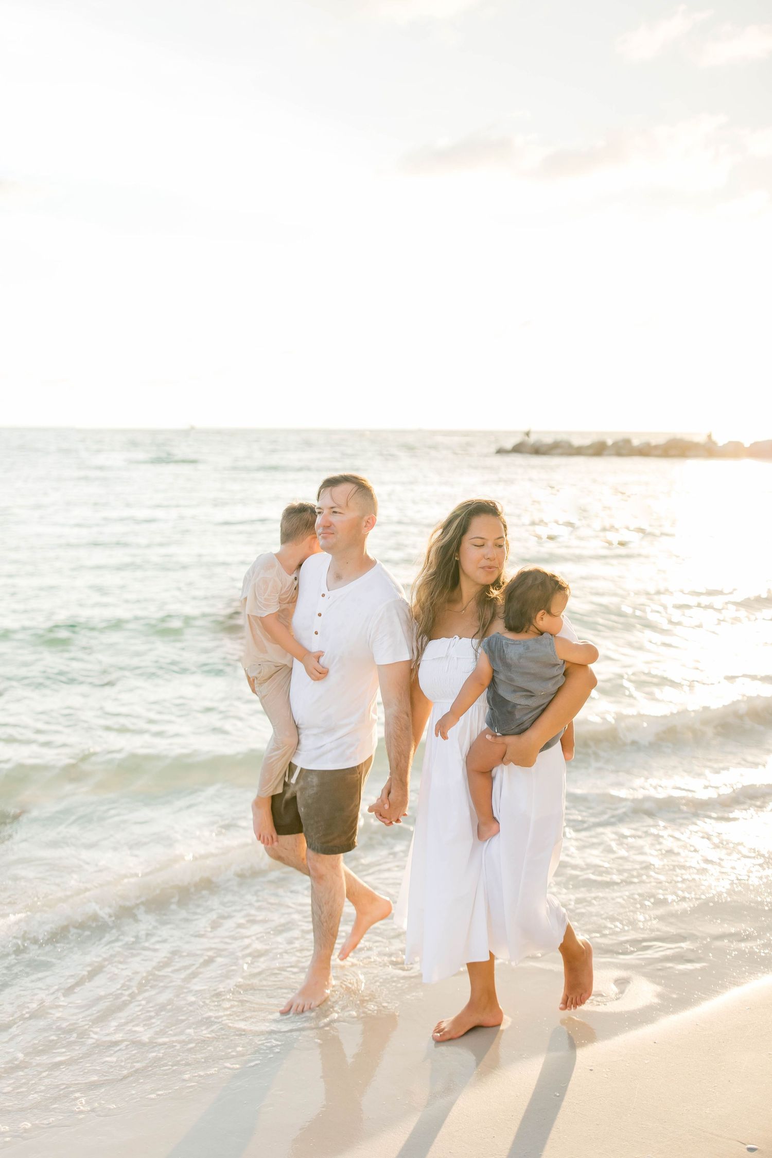 Group playing and laughing together near the ocean waves during sunset.