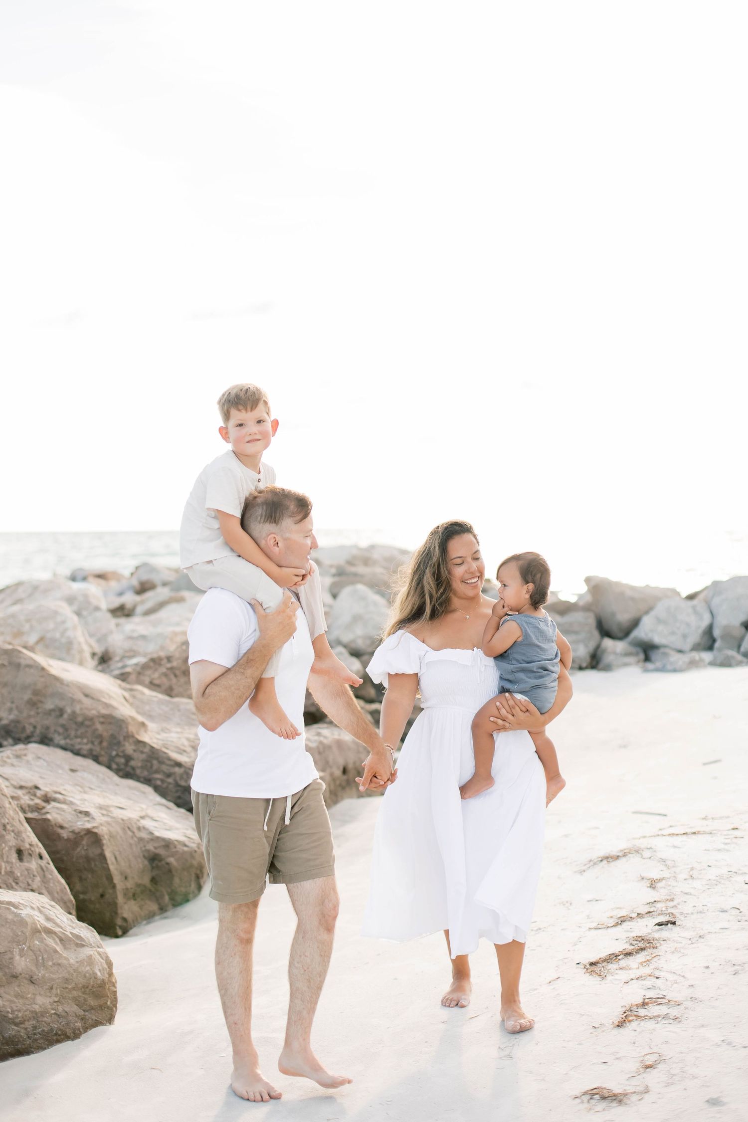 Joyful family moments captured during a beach photoshoot near rocky coastline.