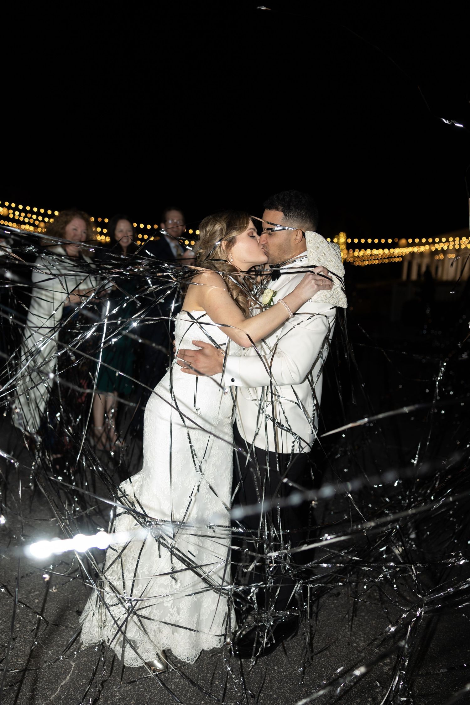 Wedding couple dancing through sparklers at nighttime celebration.