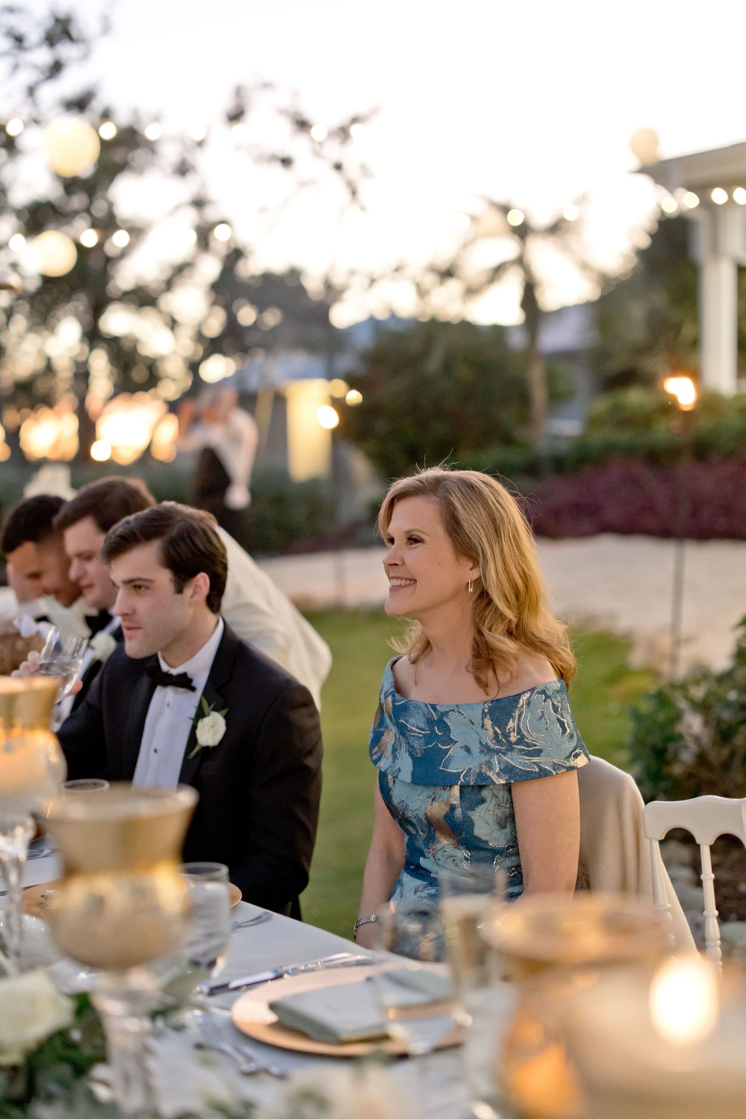 Wedding guests seated at elegant tables during sunset outdoor reception.