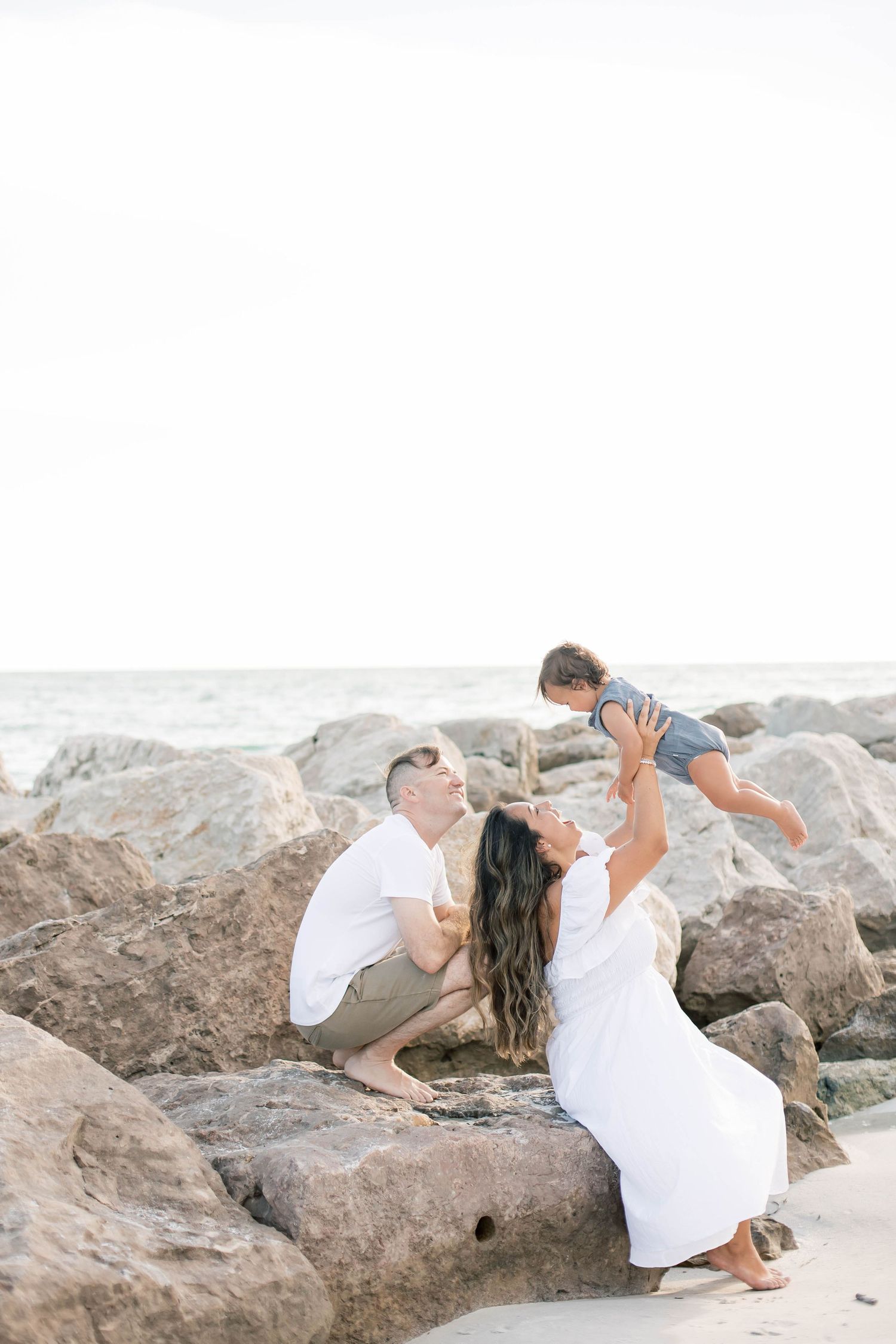 Intimate family moments captured on a rocky beach at sunset.