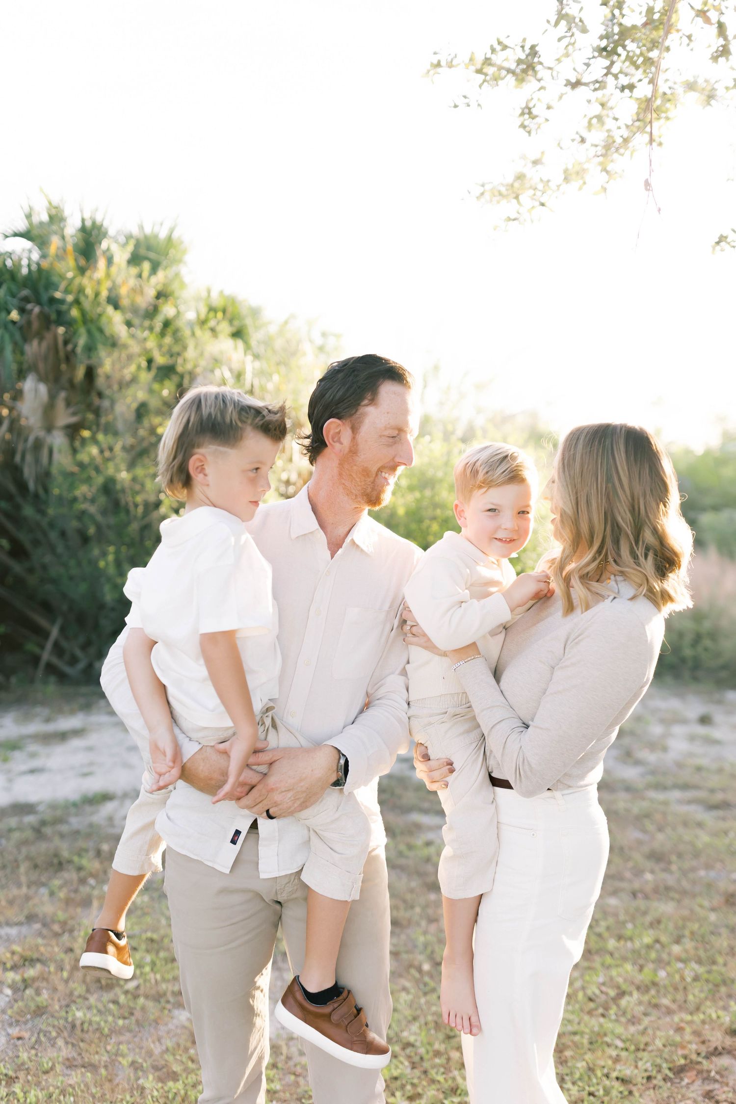 A family dressed in light colors sharing an intimate moment outdoors.