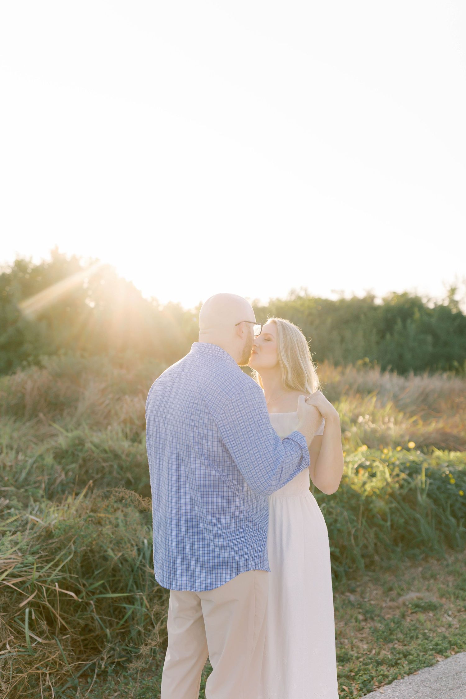 Sweet engagement moment captured in natural setting with golden sunlight.