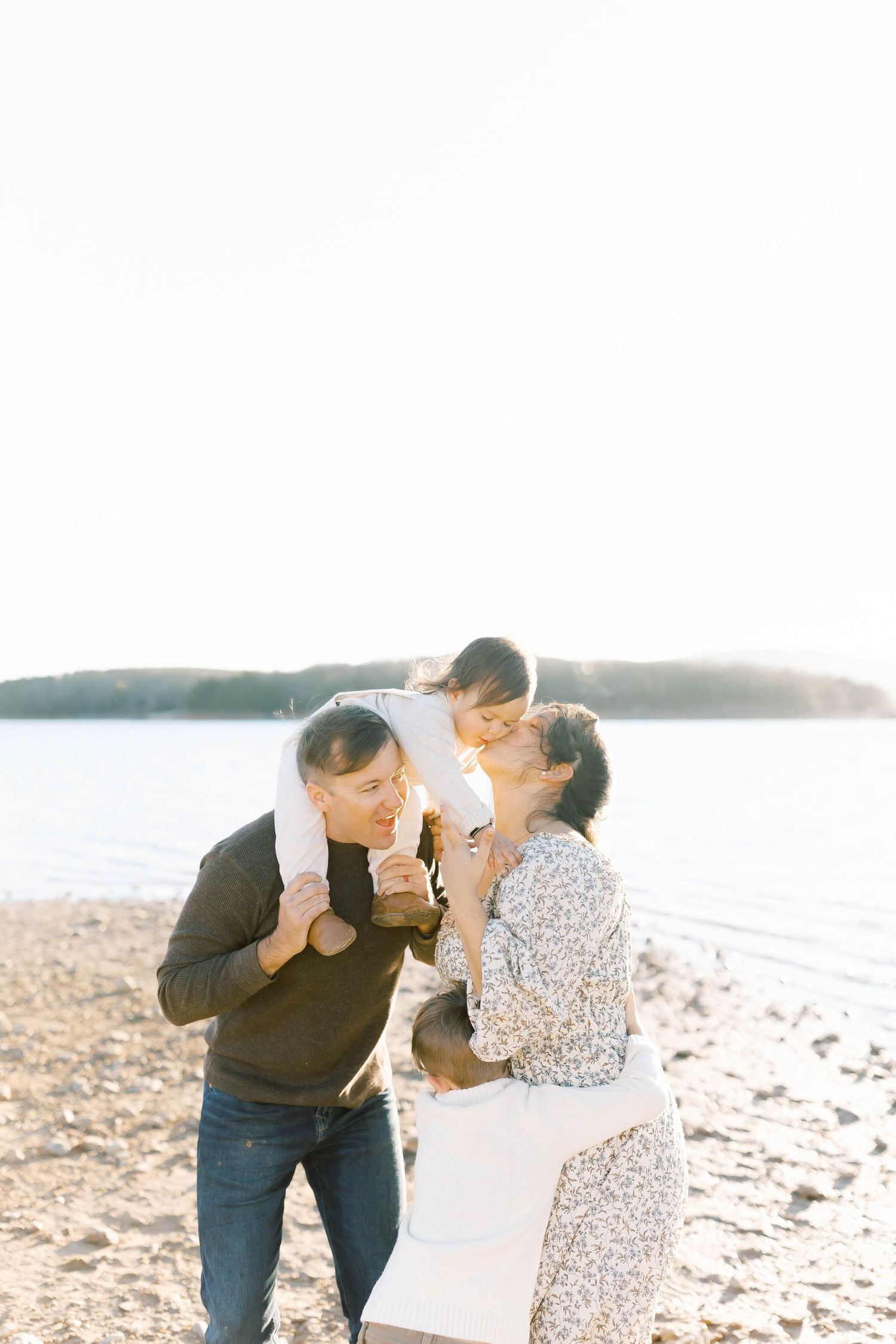 Couple shares intimate moments on rocky beach during golden hour.