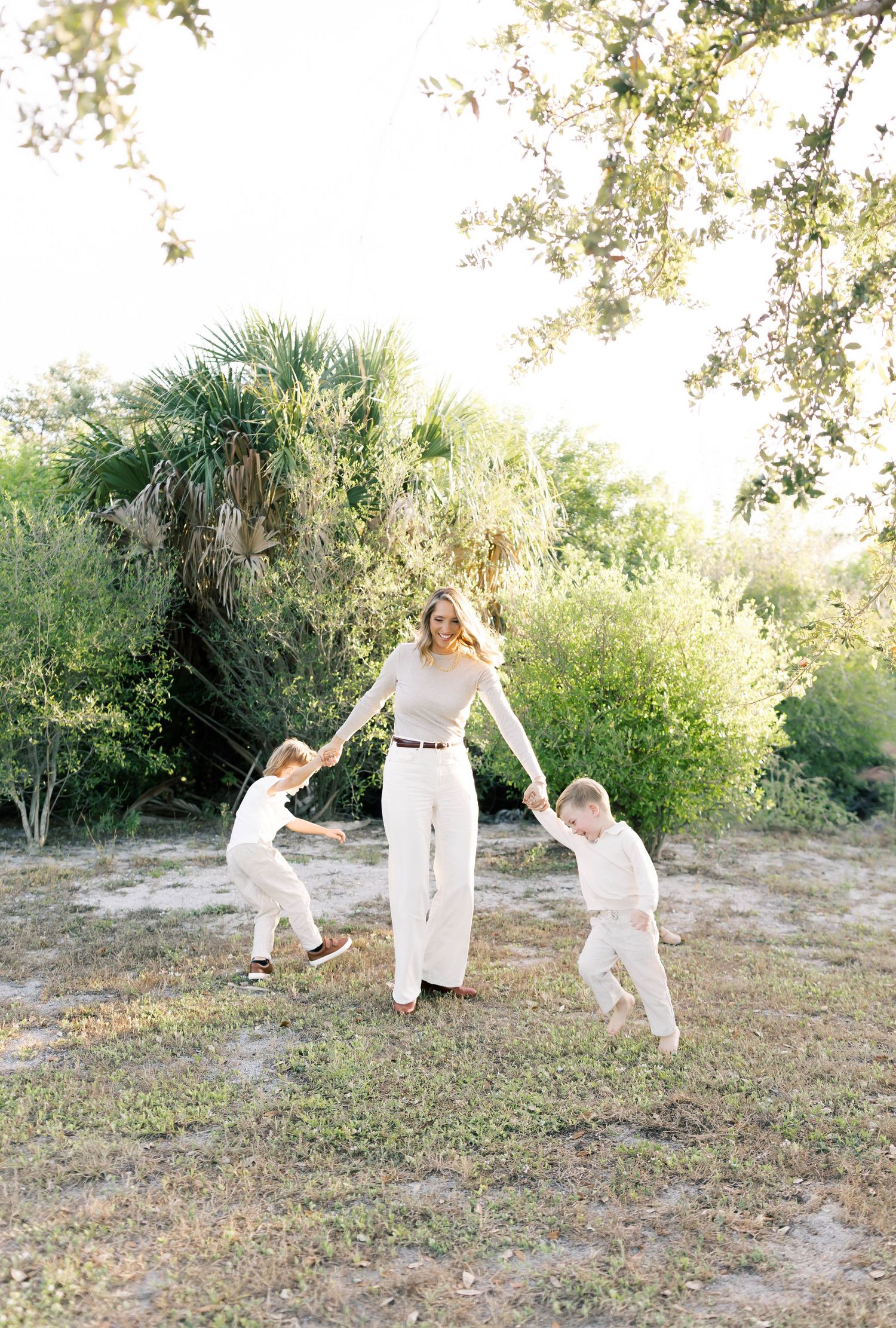 A joyful outdoor family moment with jumping and playing in a natural setting with palm trees.