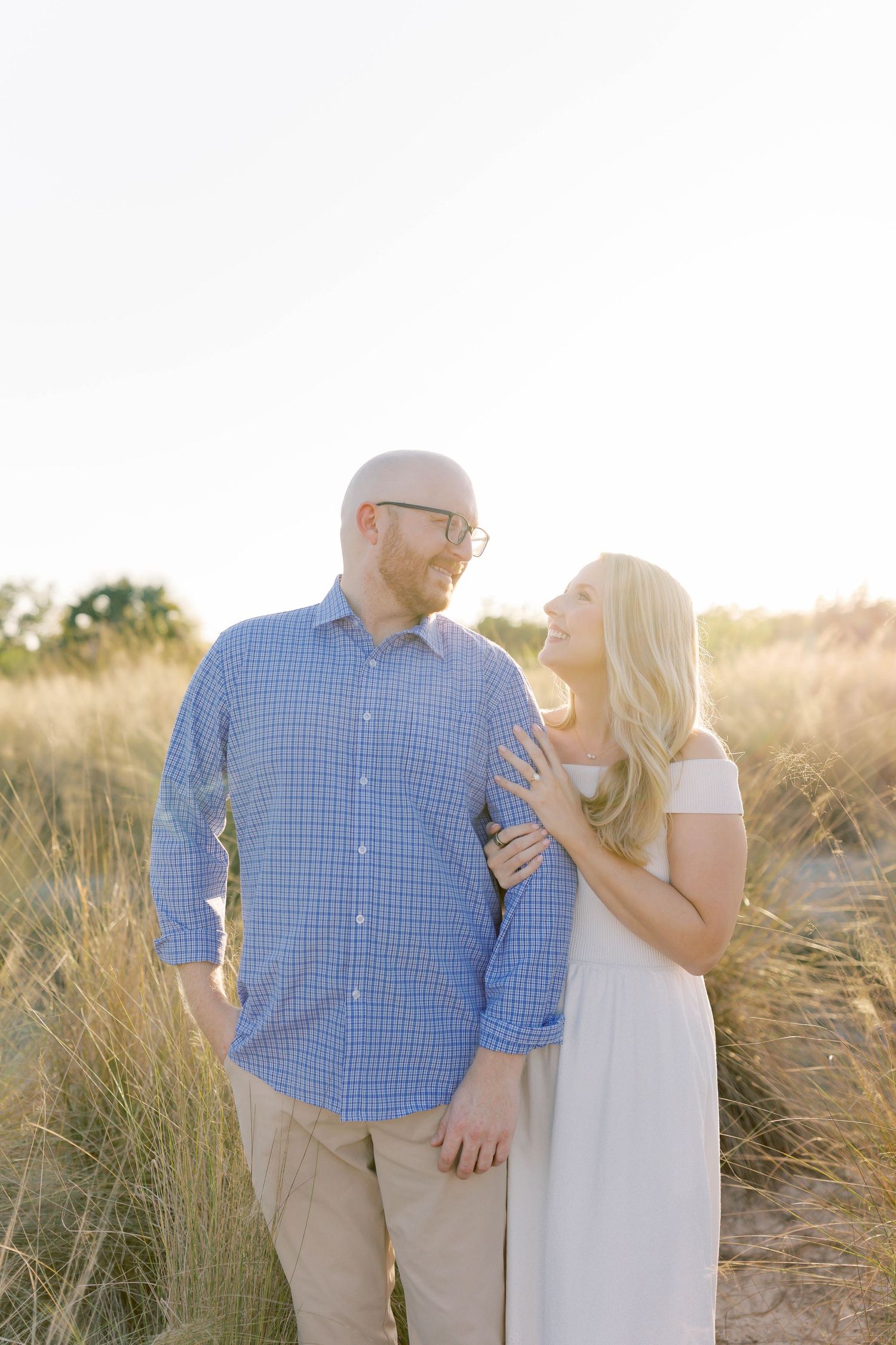 Couple shares an intimate moment while standing in a field of tall grass at sunset.
