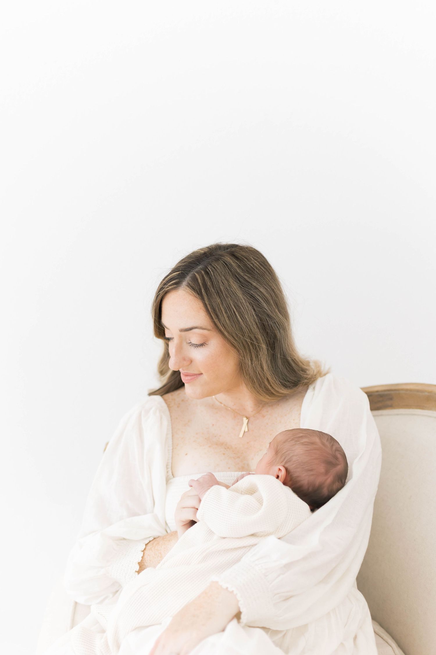 Serene moment between mother and baby in bright white studio setting.