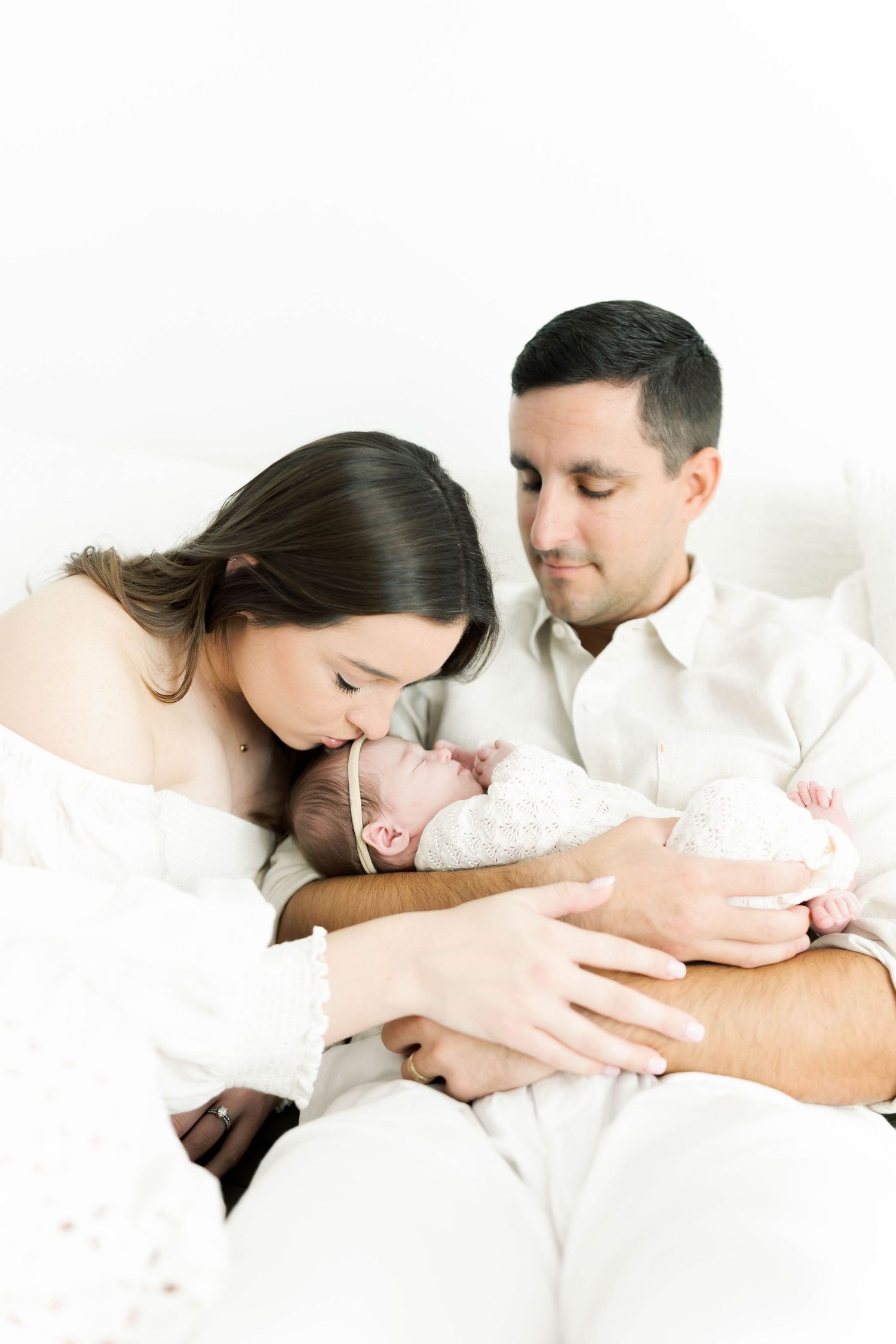 Series of intimate family moments with newborn baby in soft white tones.
