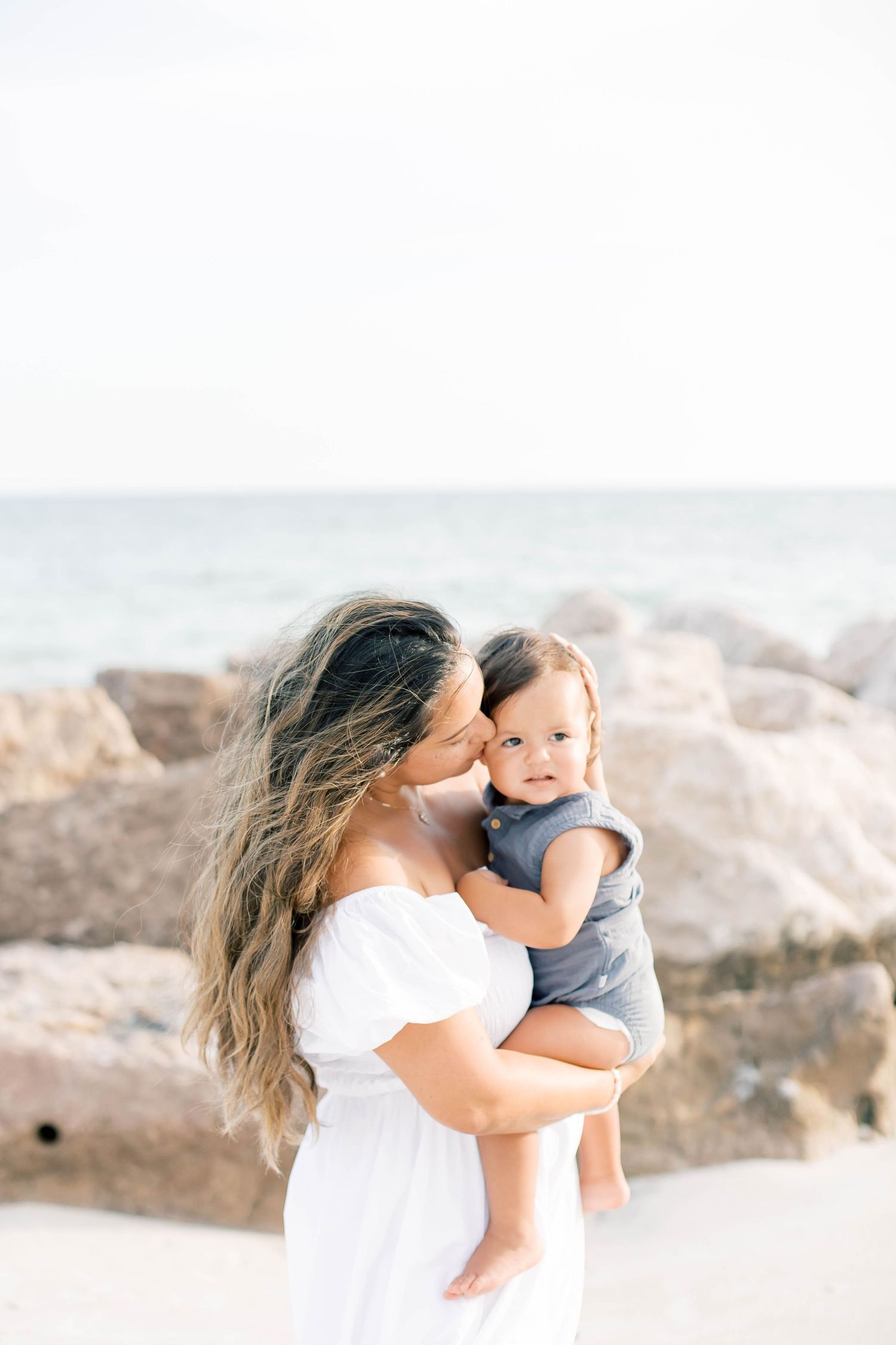 Sweet family interactions captured in soft lighting against a beach backdrop.