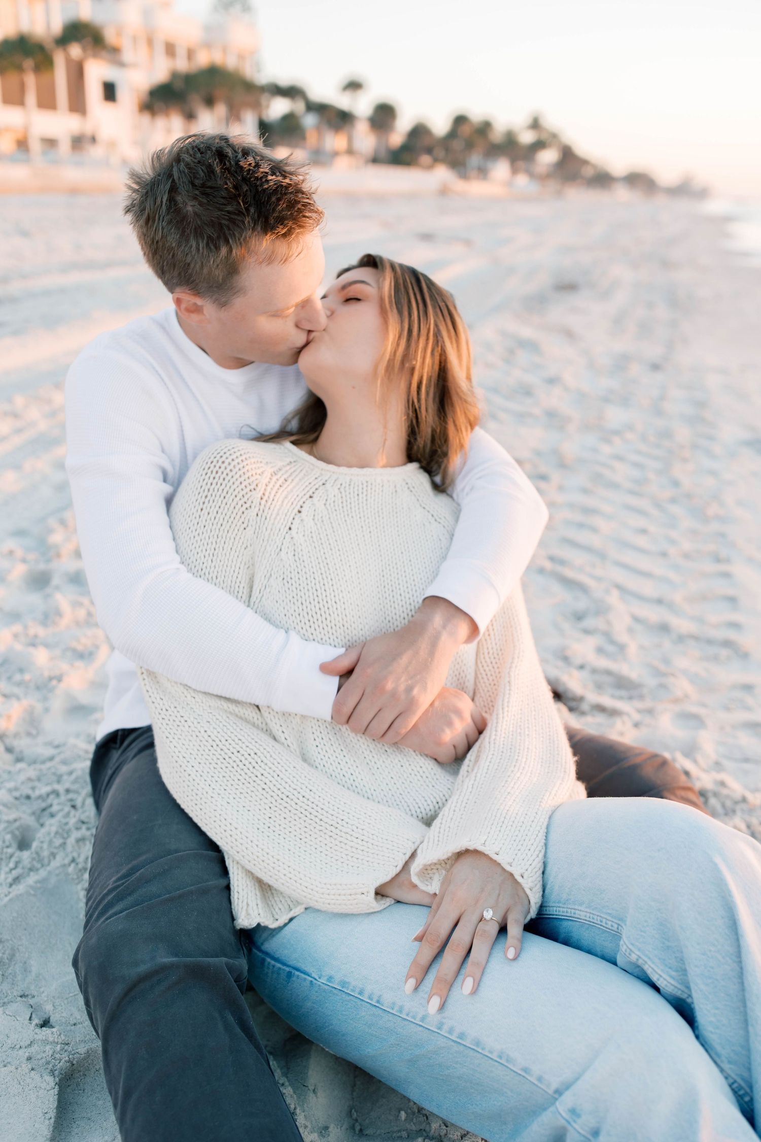 Romantic beach photoshoot with couple in casual white and denim outfits.