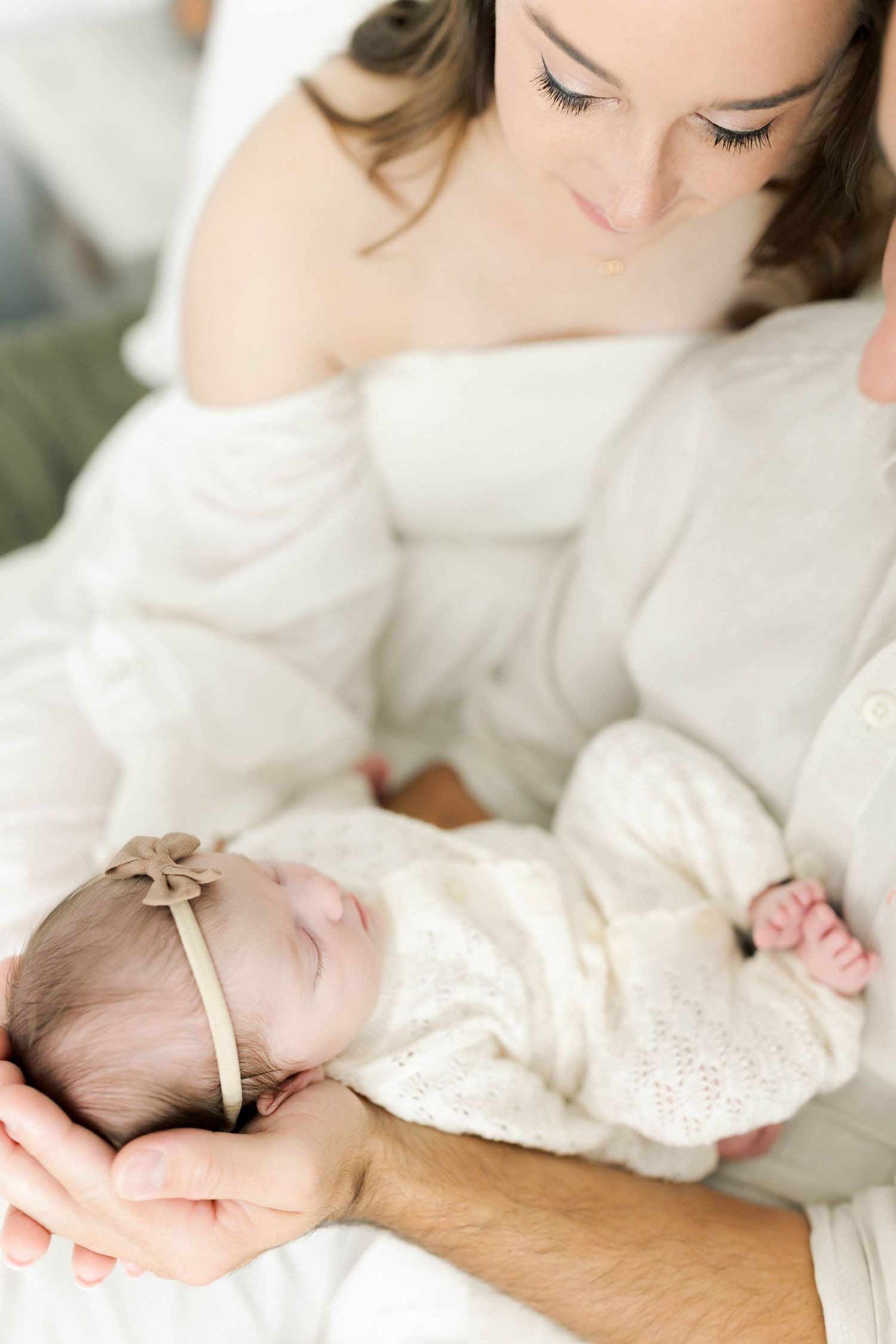 Close-up shots of tender moments with sleeping newborn in white lace clothing.