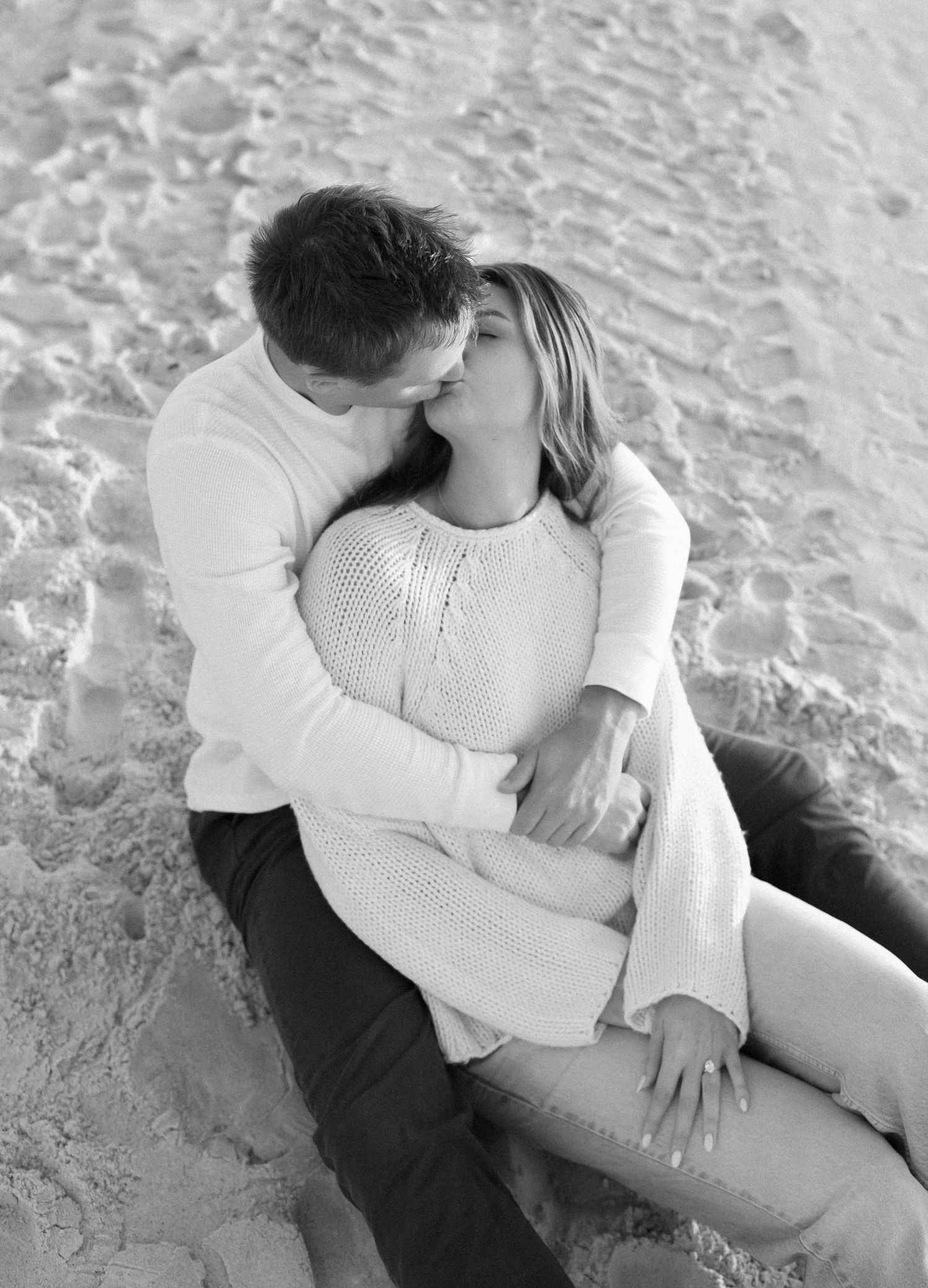 Black and white portrait of couple sharing intimate moment on beach.