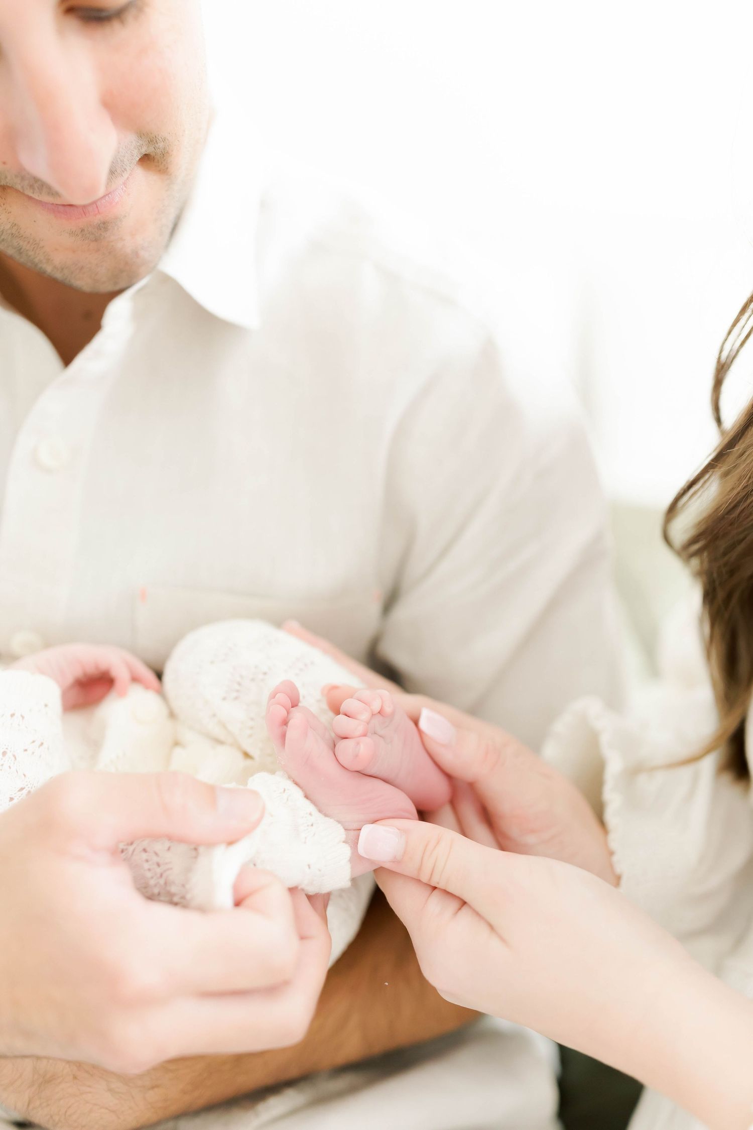 Close-up of tiny newborn feet being gently held in loving hands.