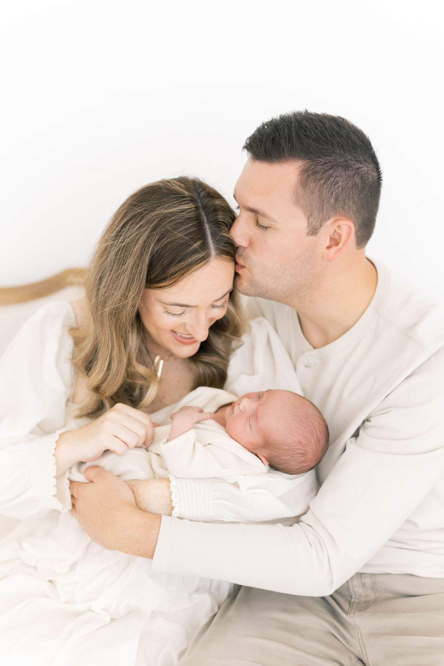 Sweet family portrait session with newborn in minimalist white studio.