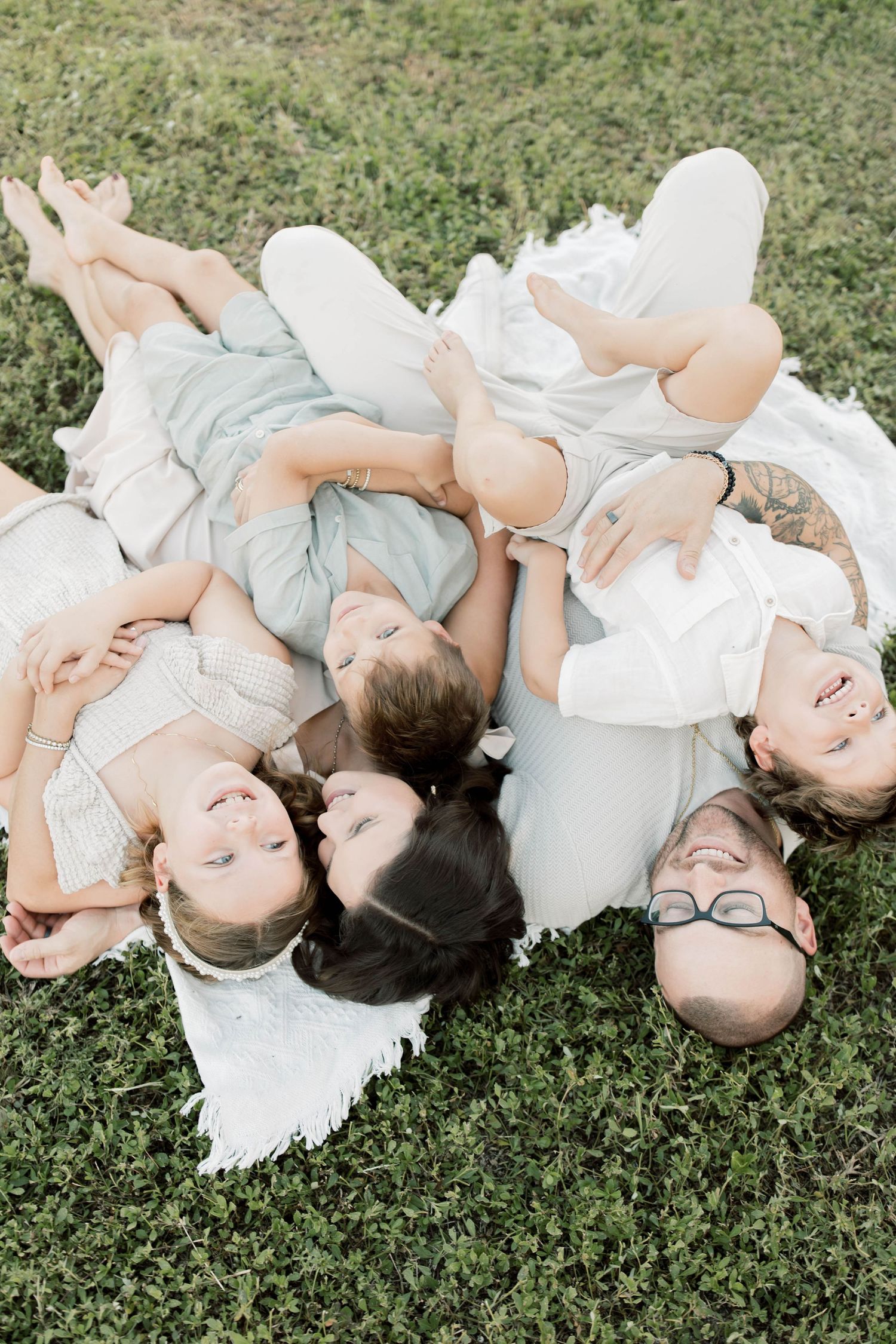 Group lying in circle formation on grass wearing coordinated light blue and white outfits.