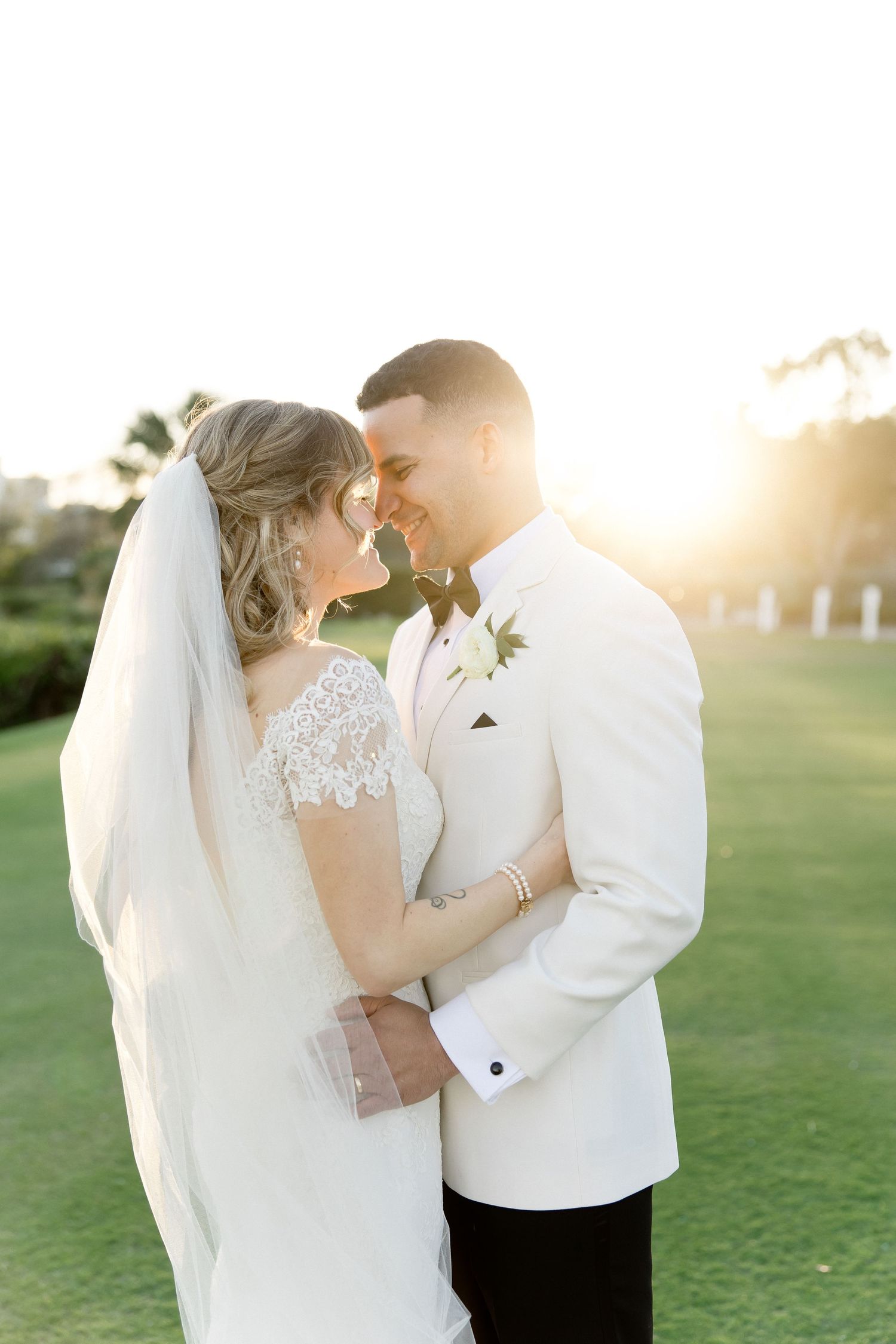 Romantic sunset wedding portraits on a lush green lawn.