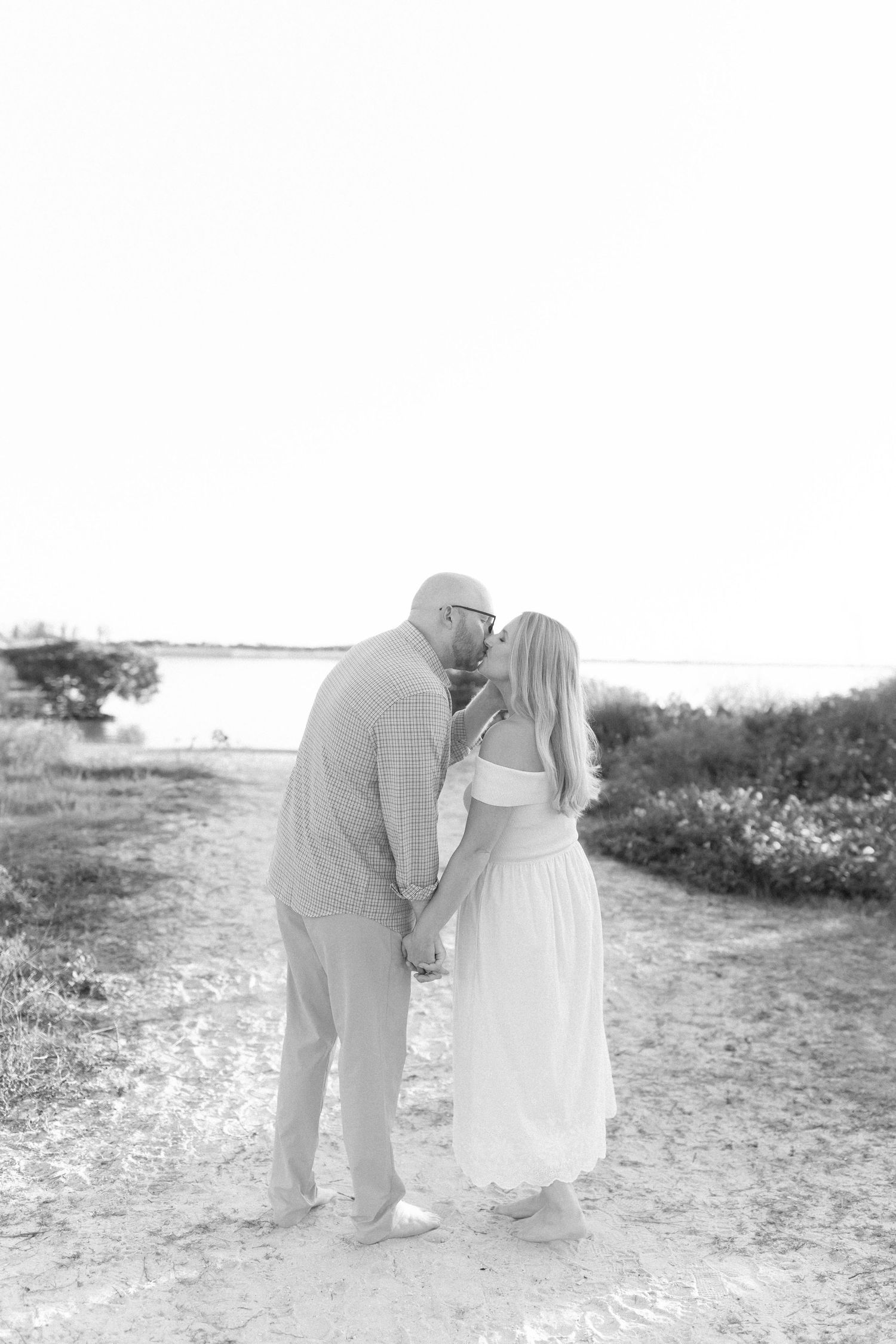 Artistic black and white capture of couple's tender moment on beach path.