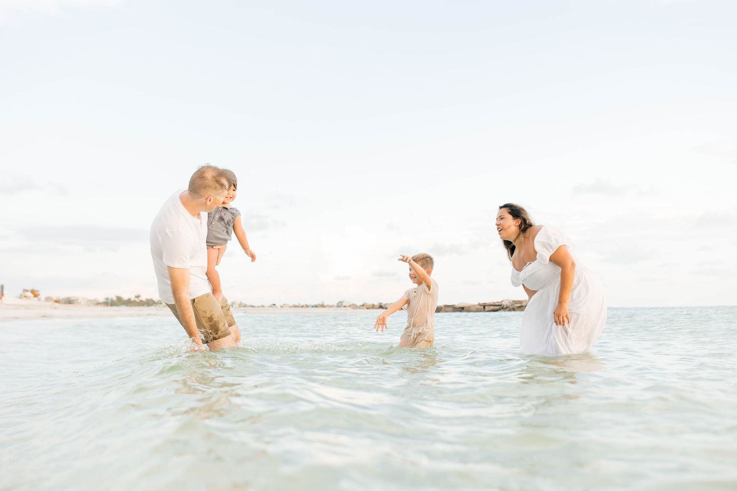Family members enjoying the waves and water during a beach day photoshoot.