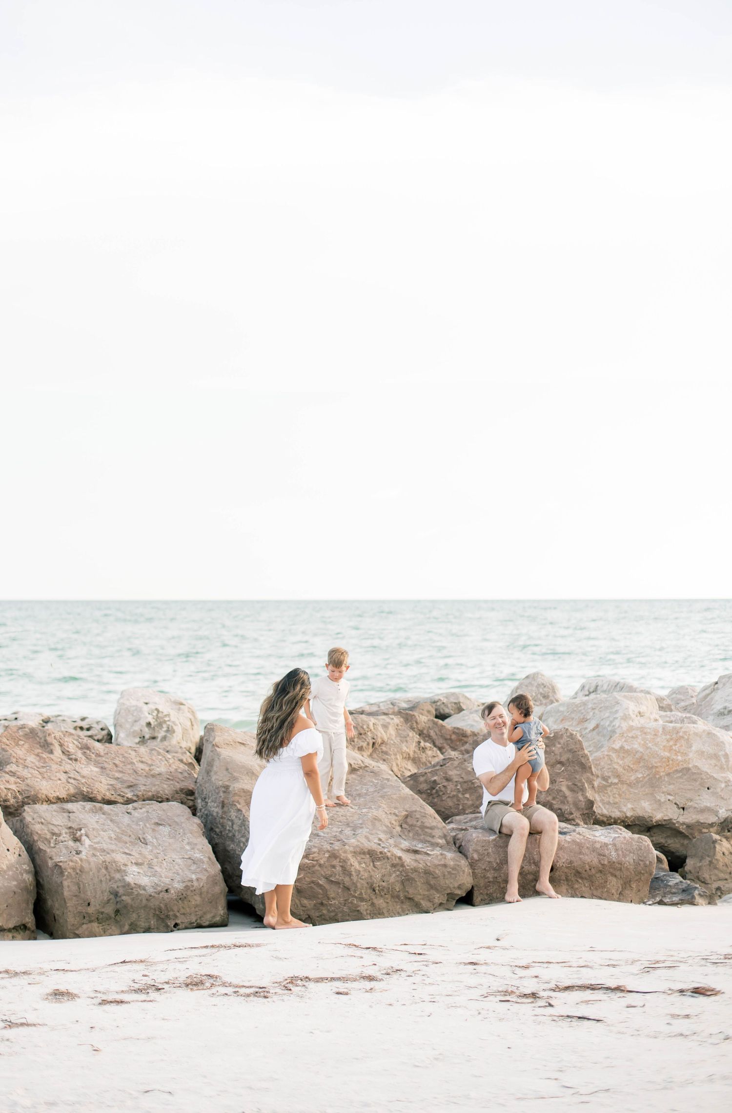 People enjoying a playful moment on a sandy beach with rocky formations in the background.