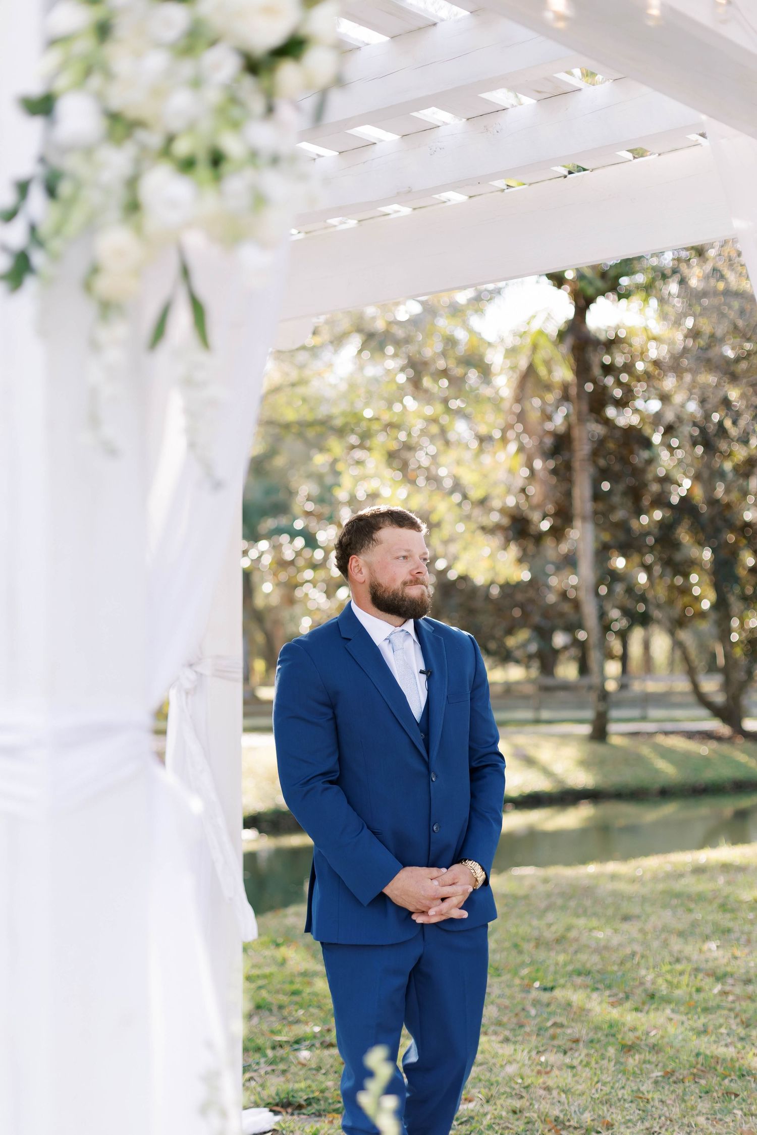Elegant white pergola decorated with flowing fabric and floral arrangements for an outdoor wedding.