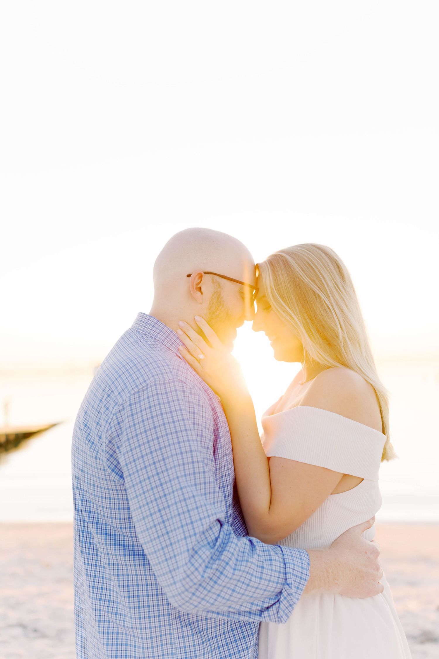 Golden sunlight illuminates loving couple's intimate beach moment.