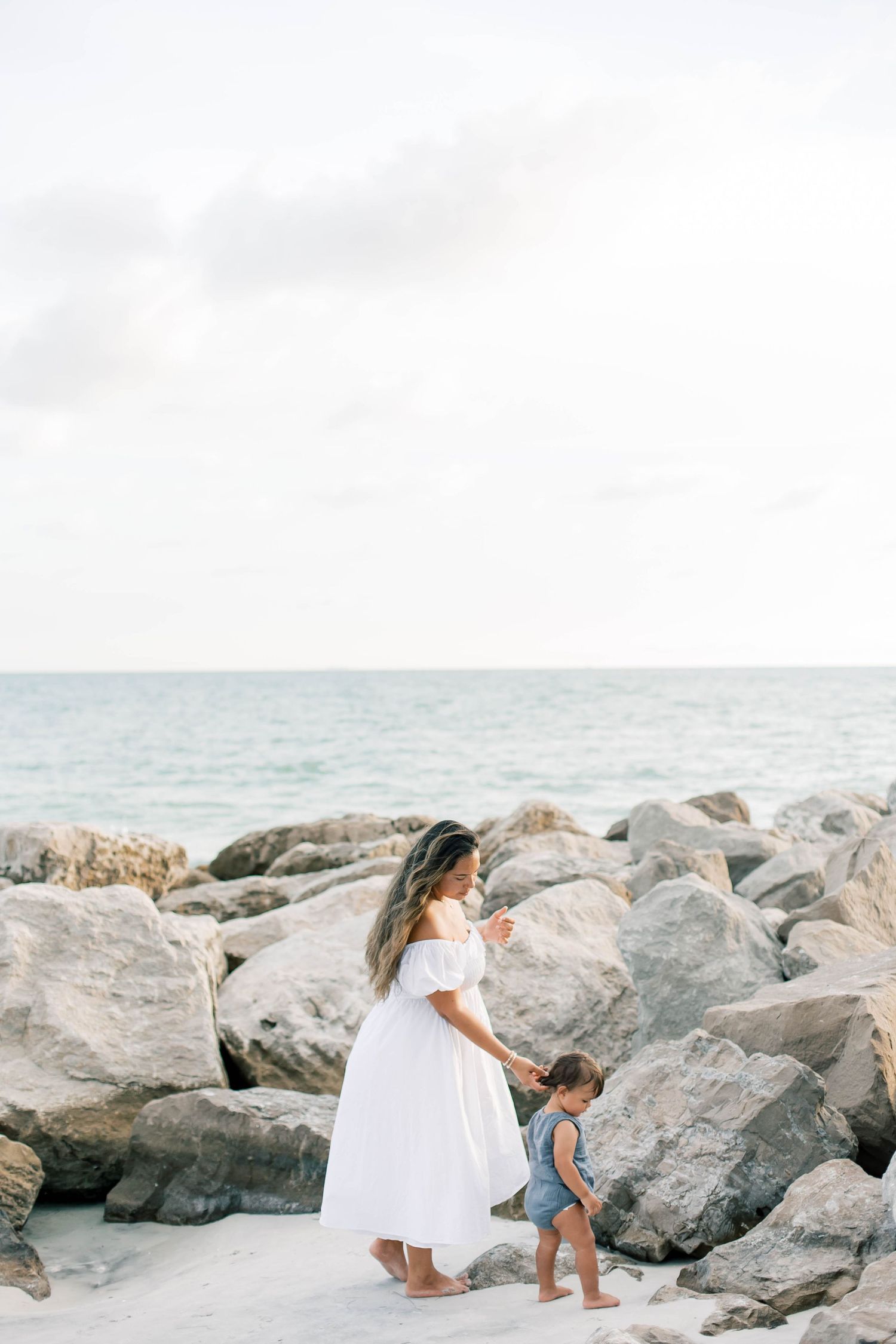 A family explores rocky formations along a peaceful beach shoreline.