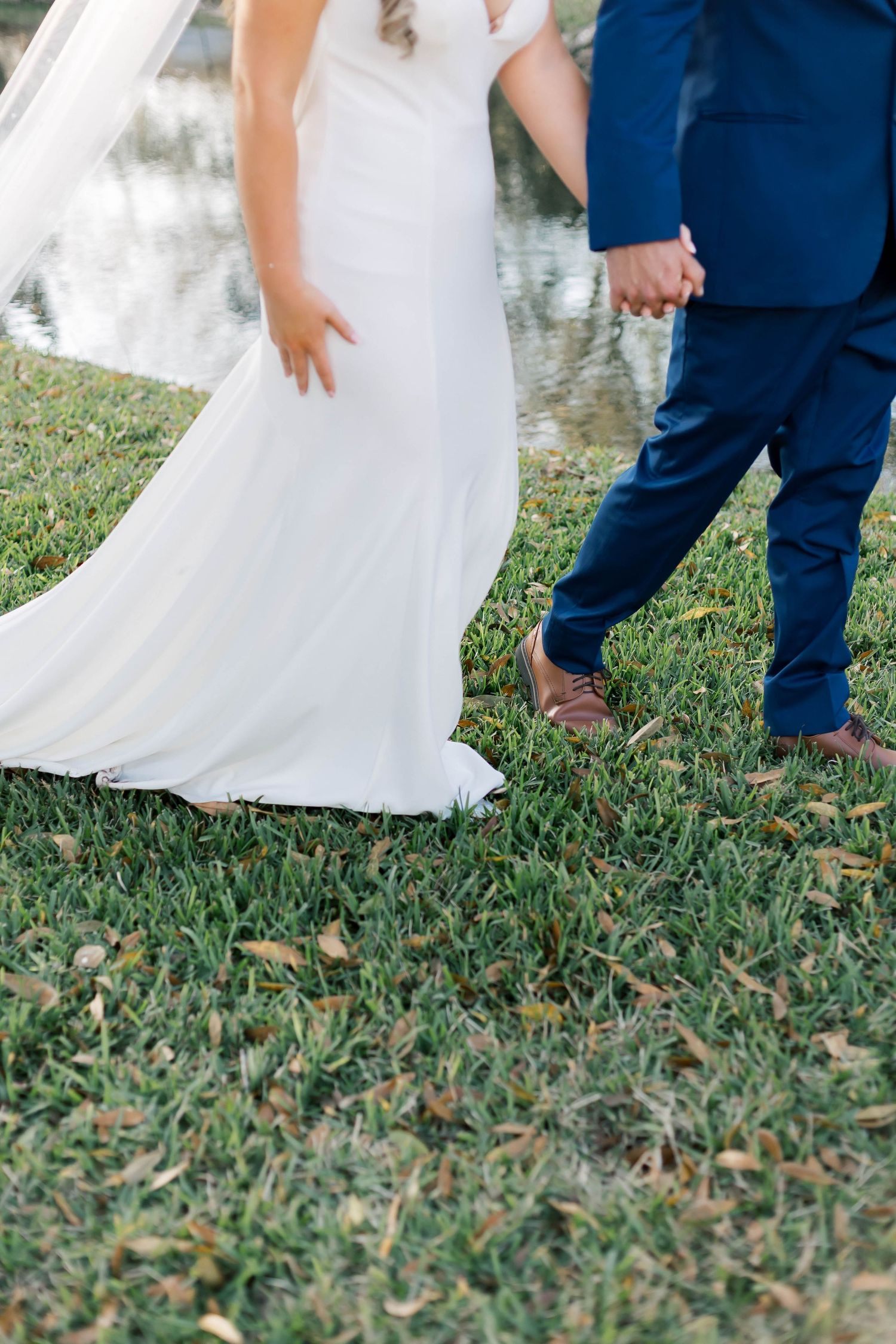 Detail shot of wedding attire and shoes on grass during outdoor ceremony.