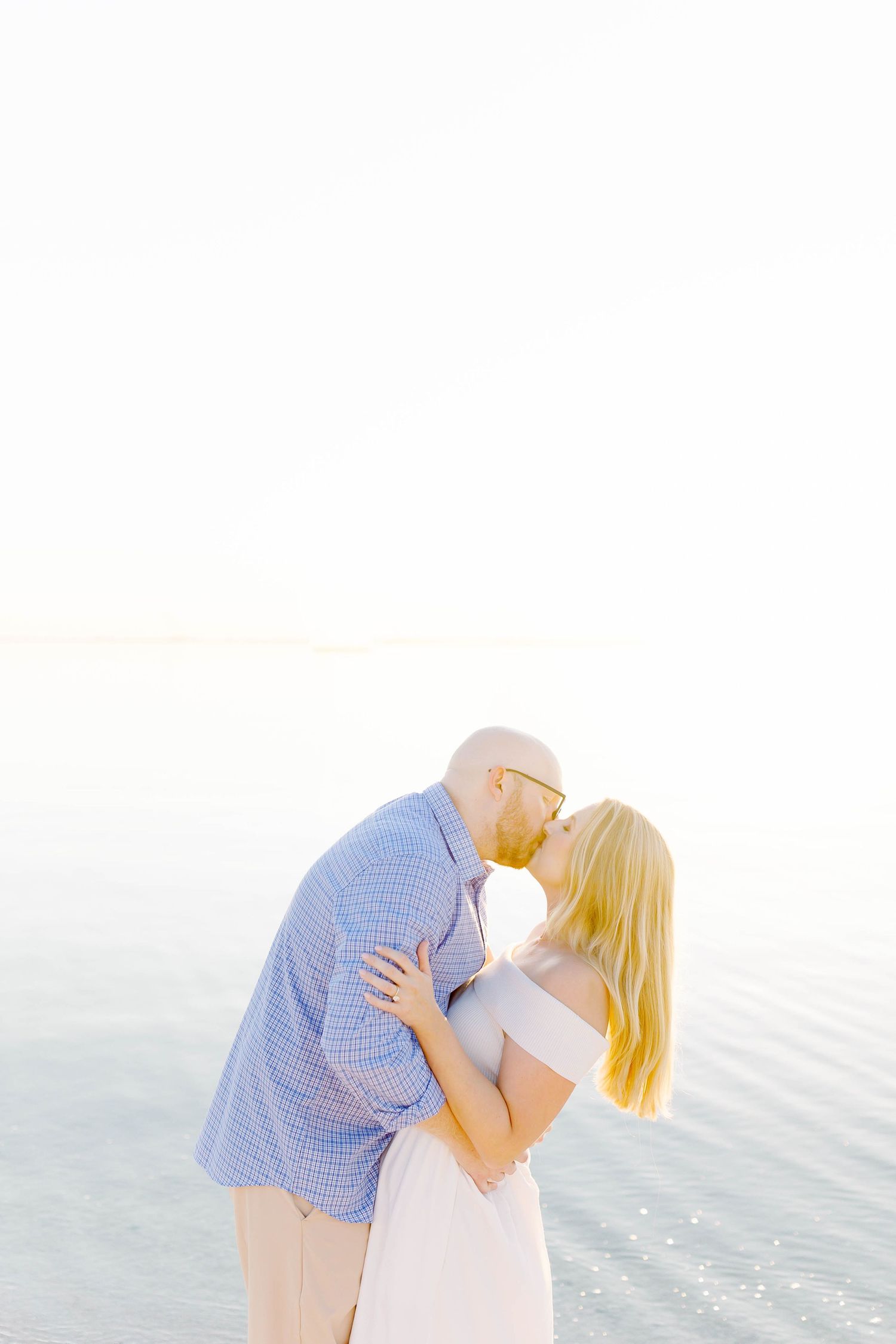 Romantic beach portrait session with couple in casual attire by the water.
