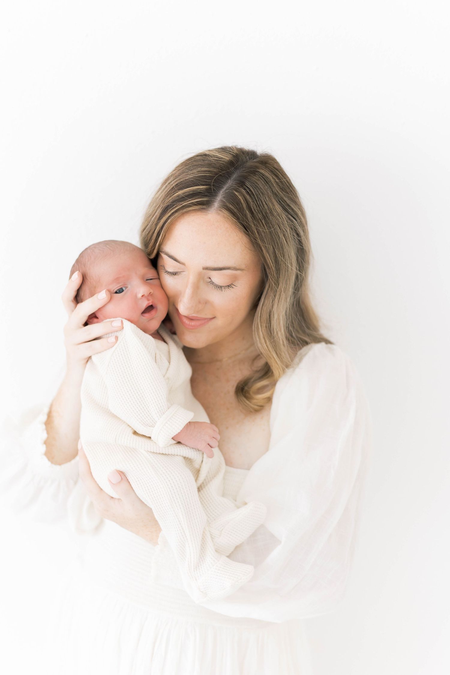 Gentle maternal moment captured in high-key photography style.