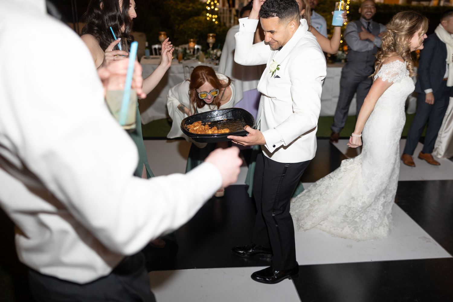 Wedding reception dance floor with guests celebrating under string lights.