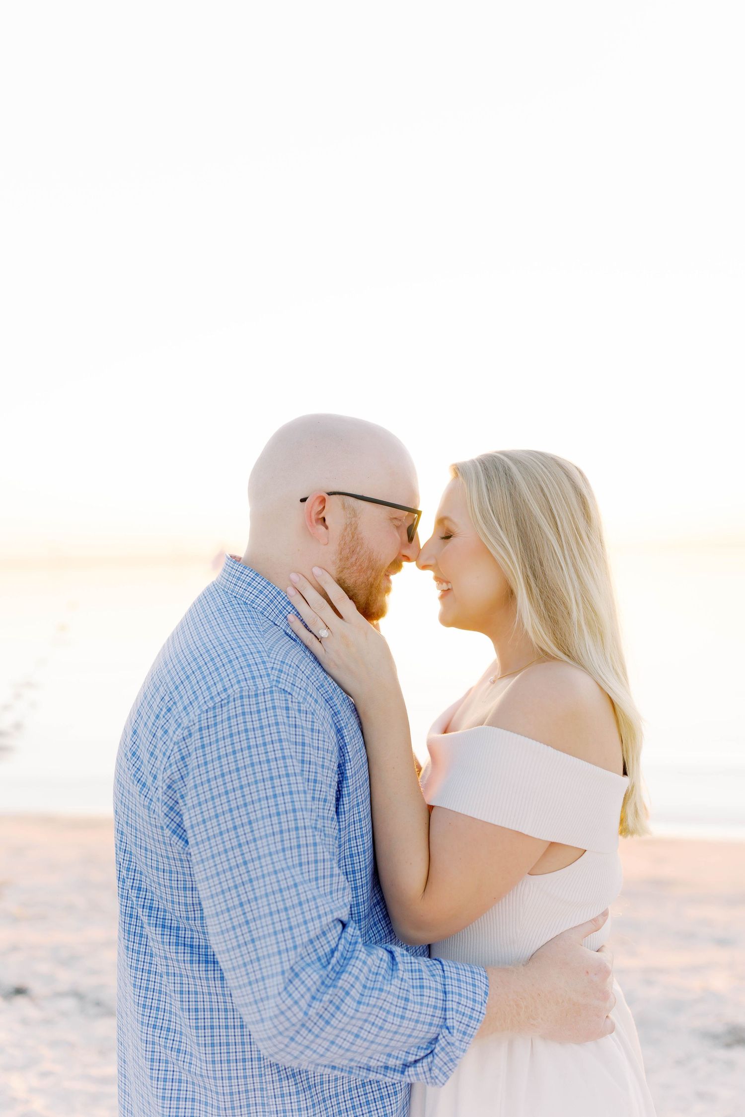 Couple shares romantic kisses during sunset photoshoot on beach.