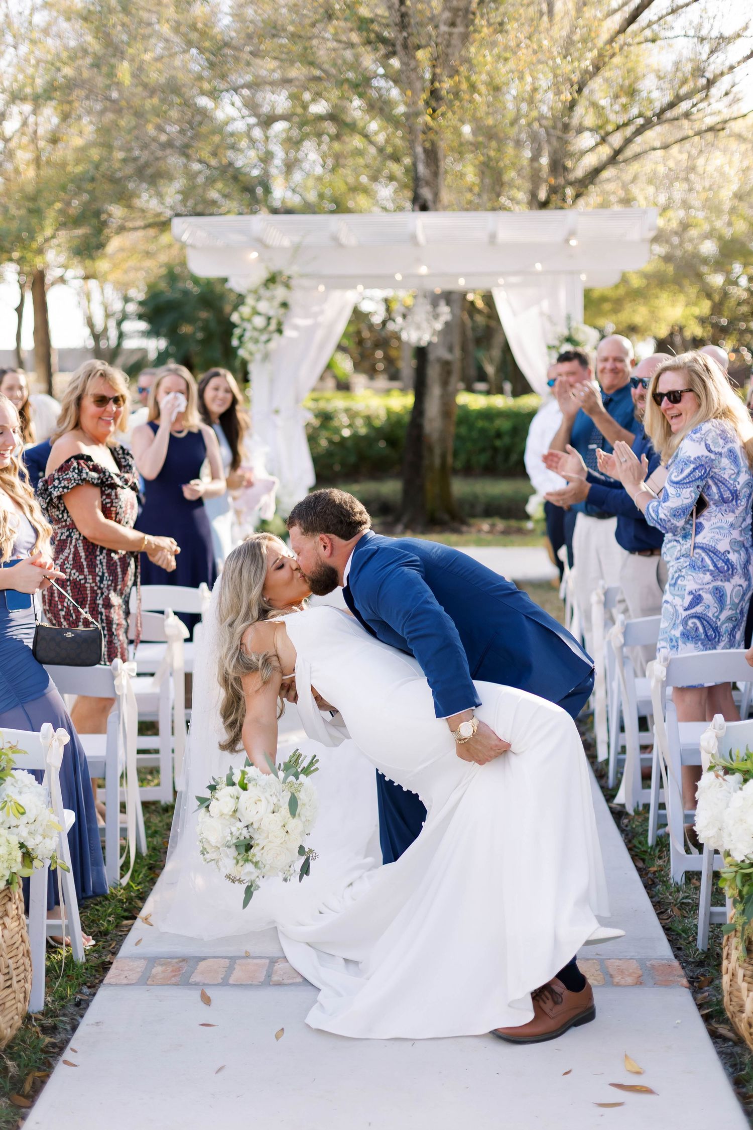 Joyful wedding celebration with guests watching couple's first dance outdoors.