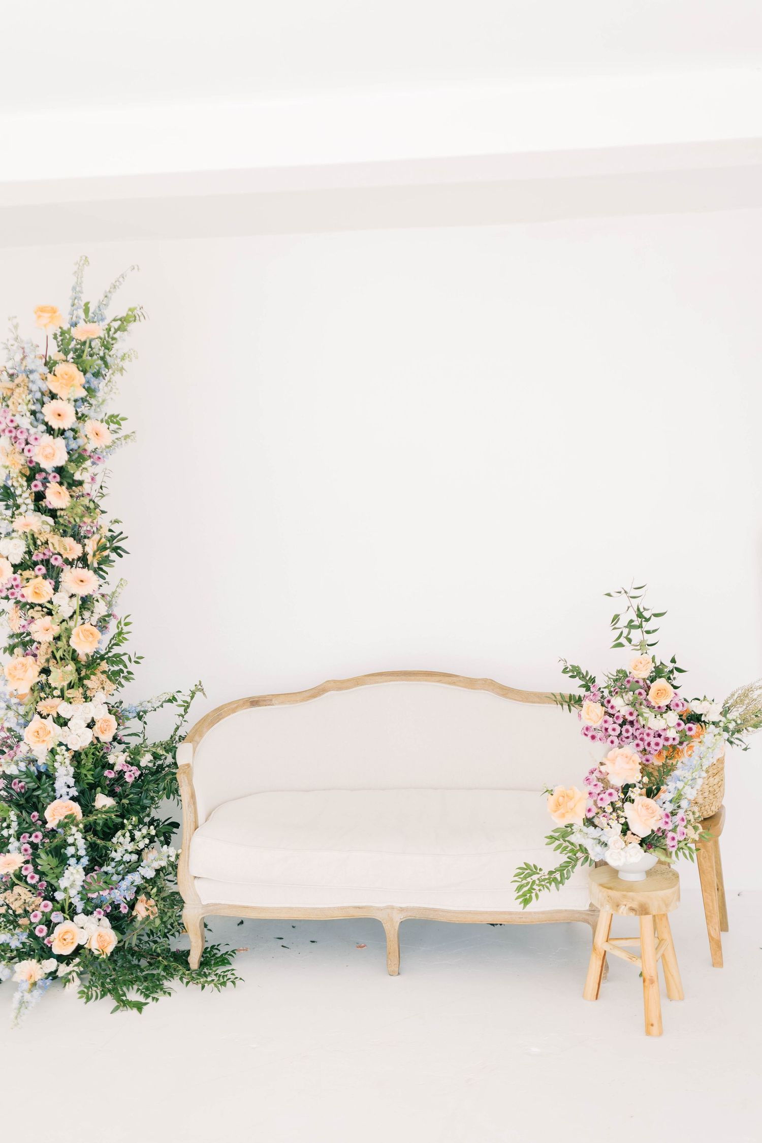 Elegant white French sofa with lush floral arrangements in pink and white against a bright backdrop.
