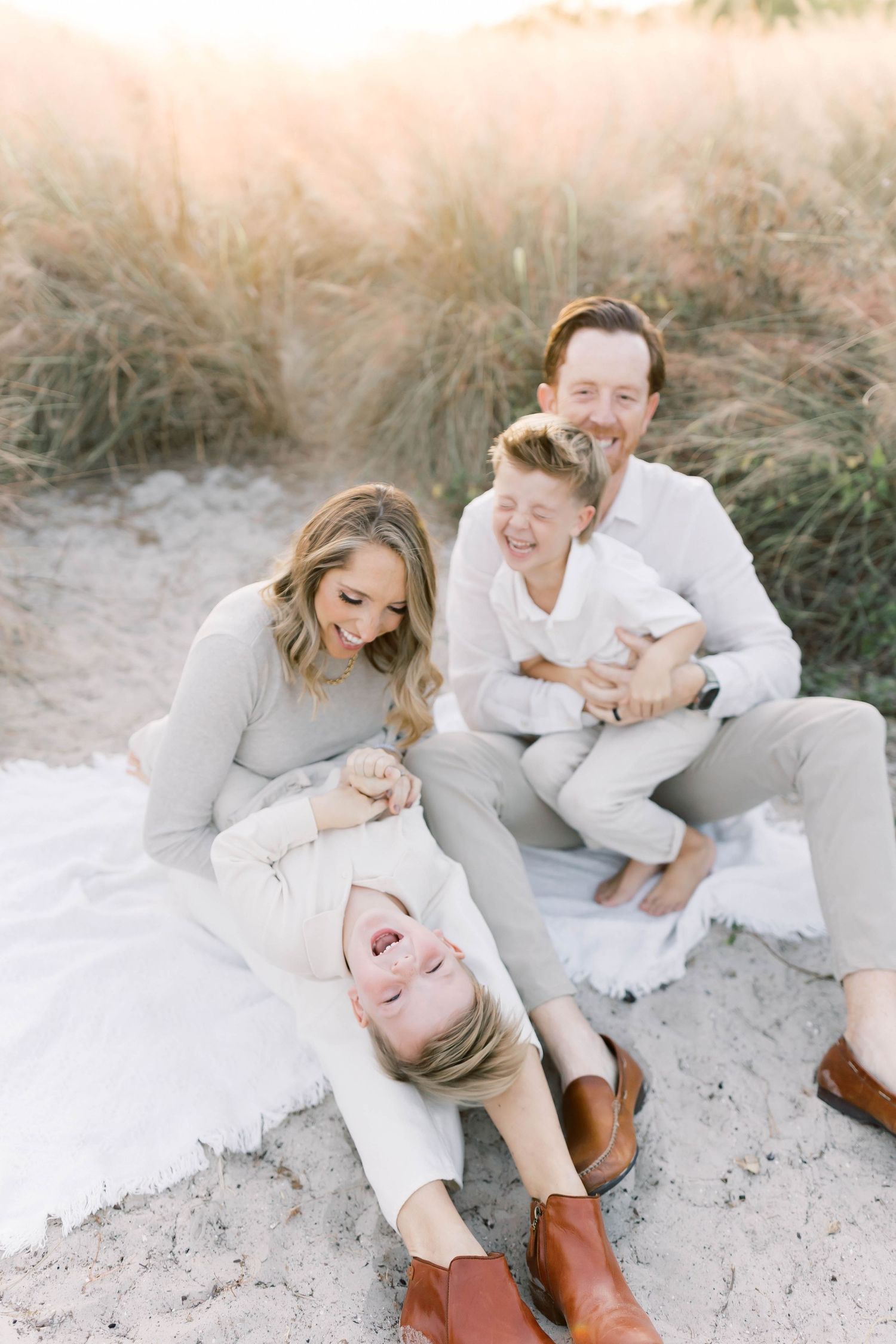 Candid family moments captured on beach with everyone wearing coordinated white and beige outfits.