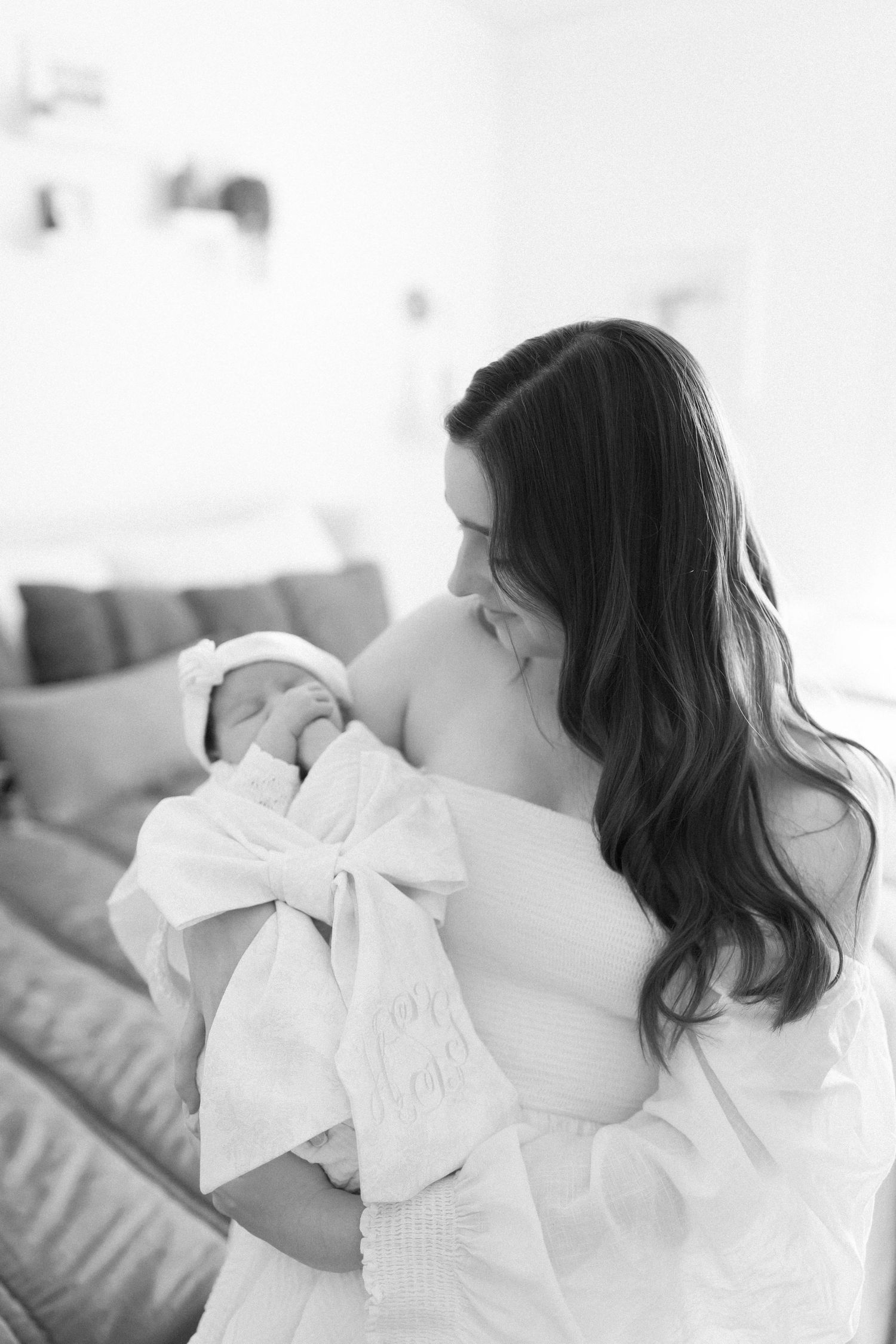 Intimate black and white portrait of mother and baby in soft natural light.
