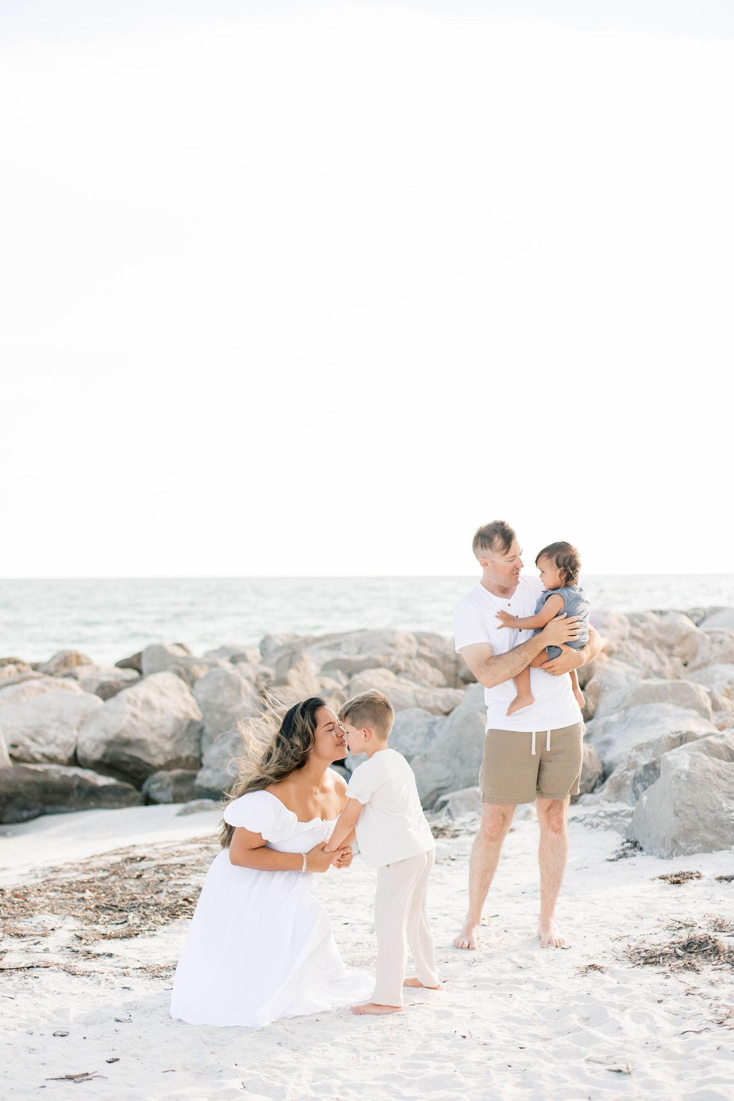 Candid family photos on a white sandy beach with large boulders.